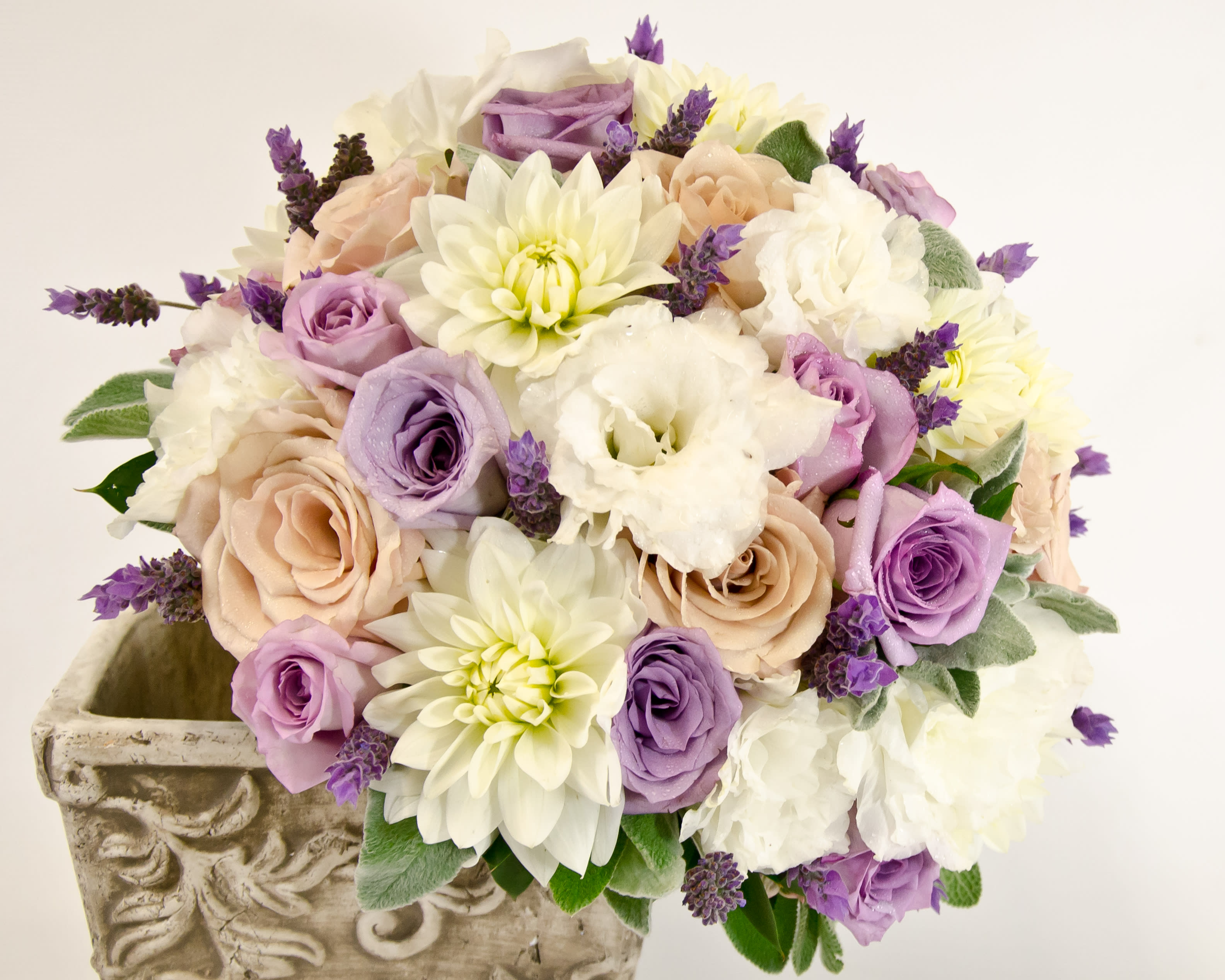 Bouquet of lavender, cream, and blush flowers in a decorative stone planter