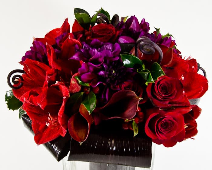 Red roses, purple flowers, and dark calla lilies in a black vase