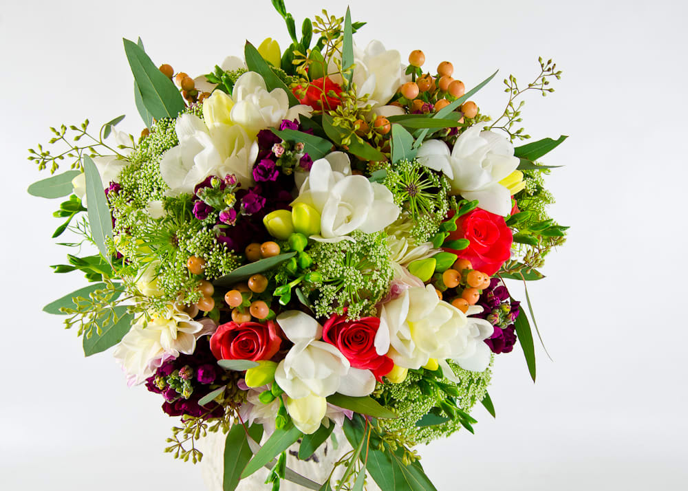 Bouquet of white orchids and red roses with mixed greenery
