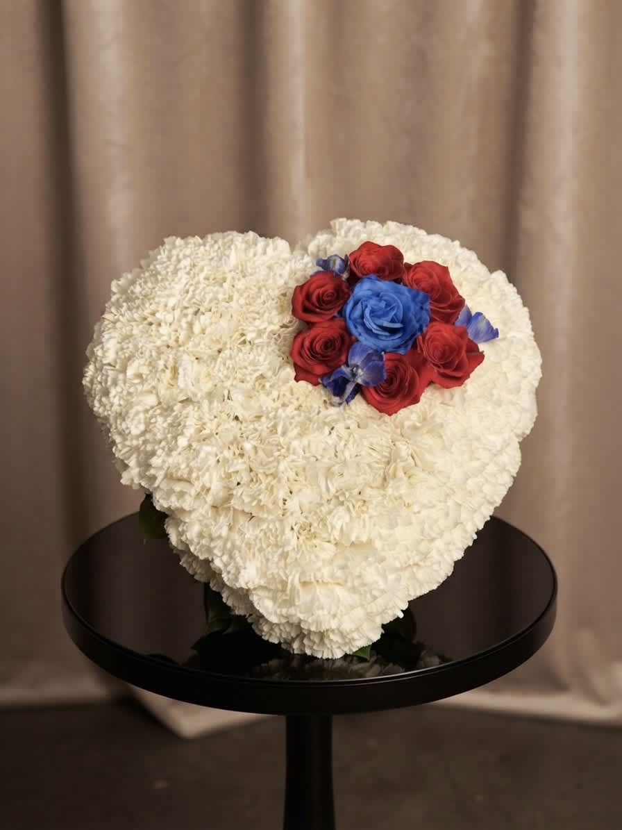 Heart-shaped white floral arrangement with red and blue roses