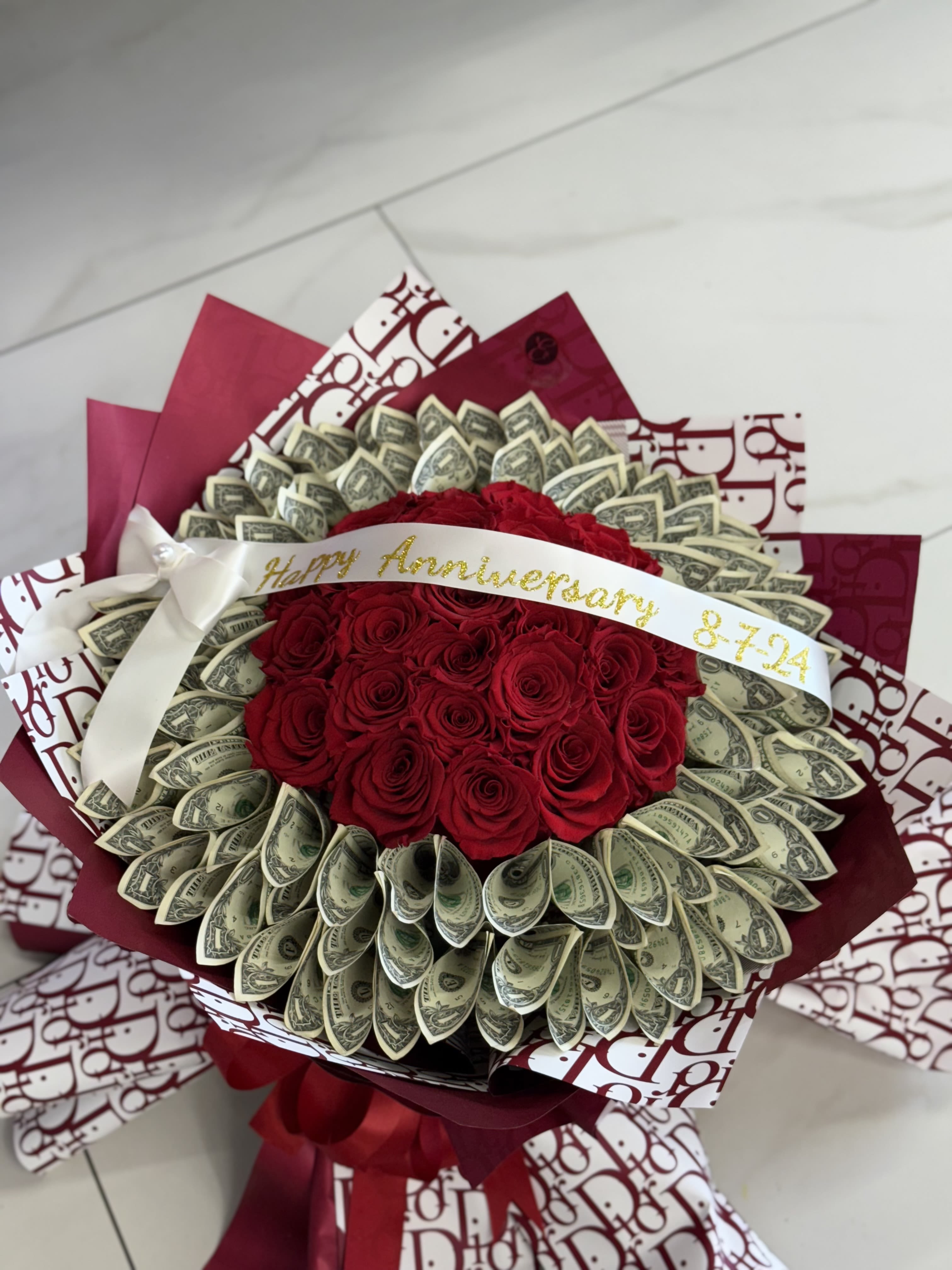Bouquet of red roses wrapped with dollar bills and burgundy paper