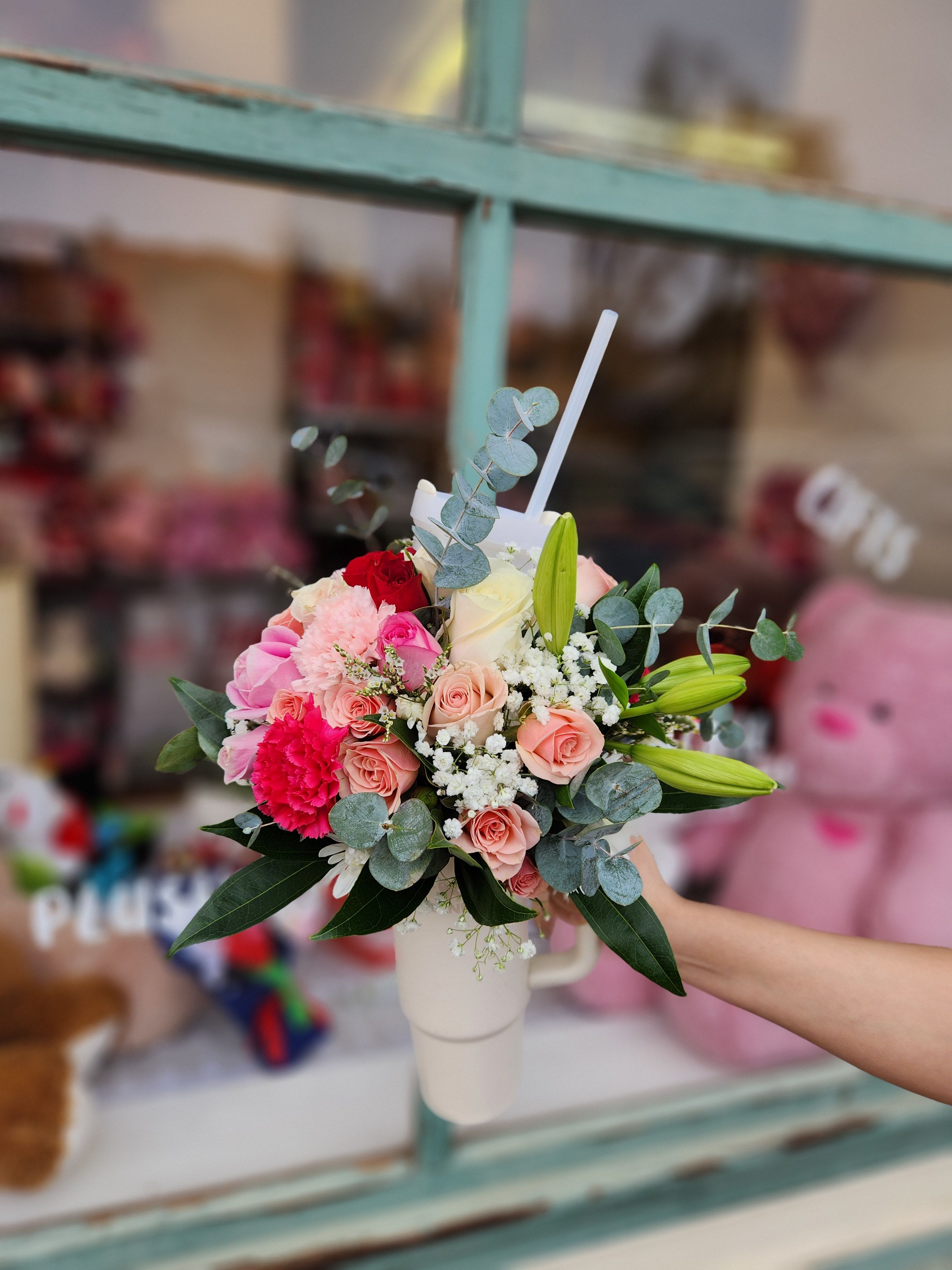 Mixed bouquet of pink and white flowers in a white mug vase