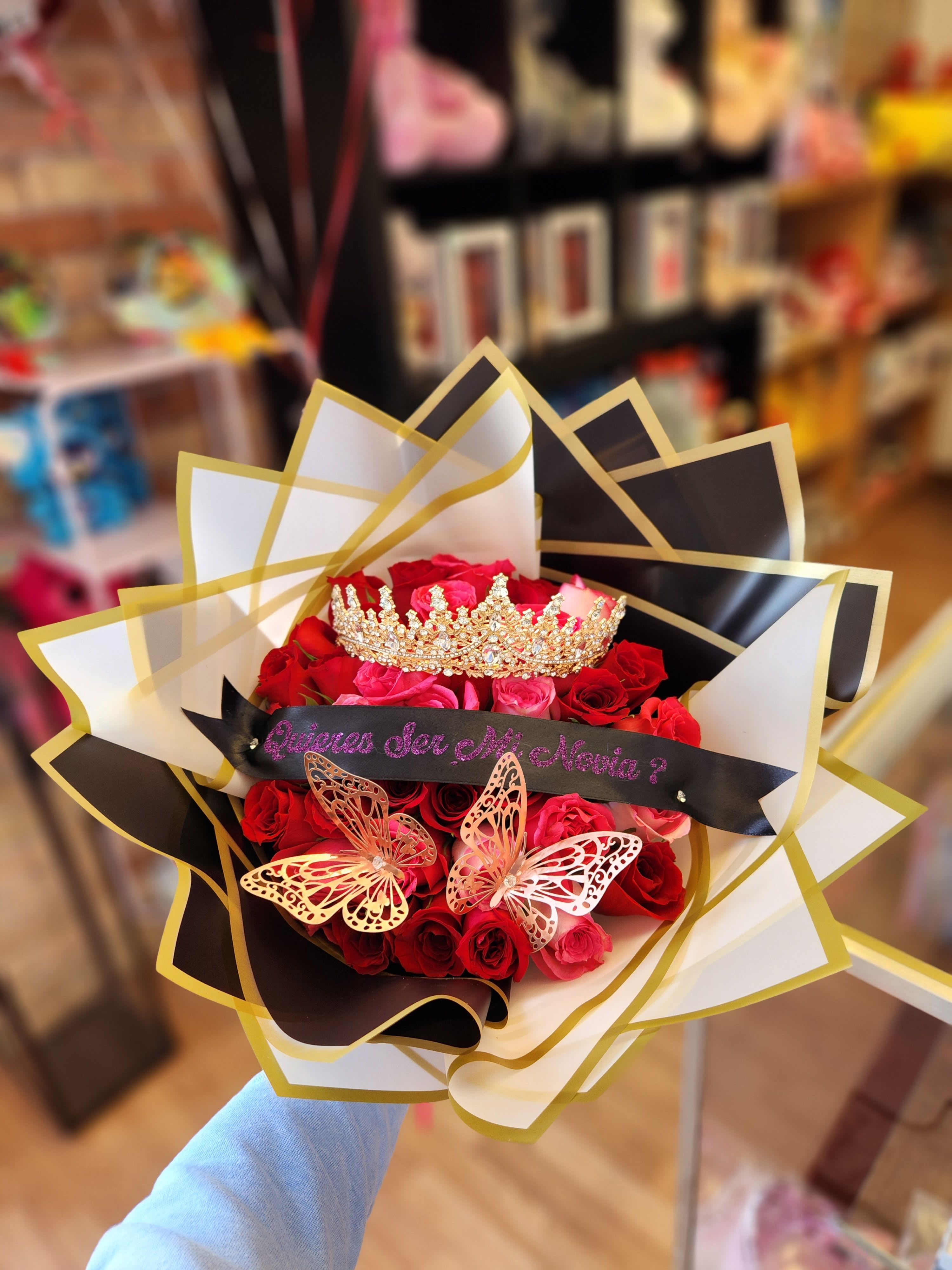 Bouquet of red and pink roses with a jeweled crown and butterfly decorations