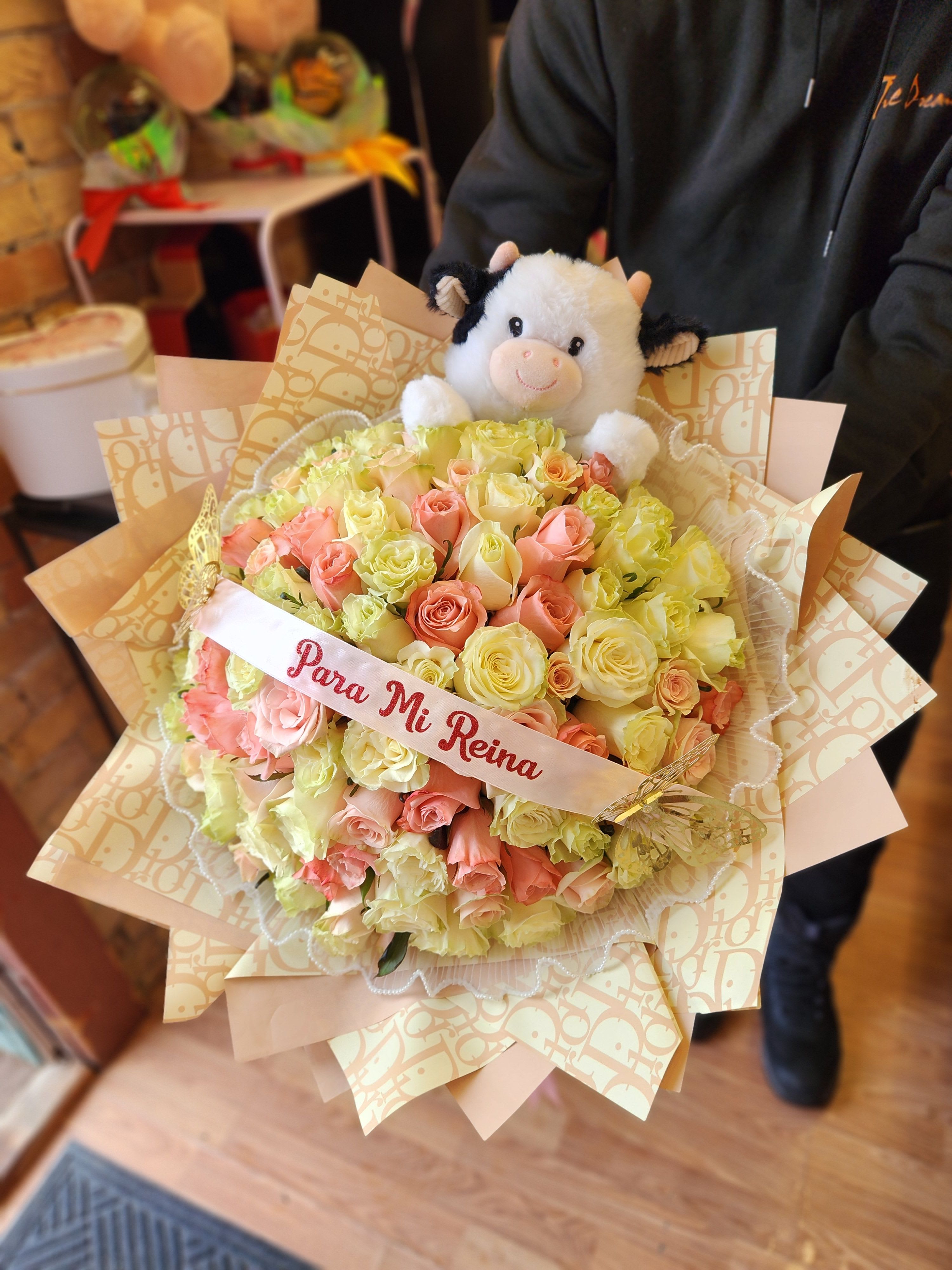 Bouquet of pink and pale yellow roses with a plush cow topper