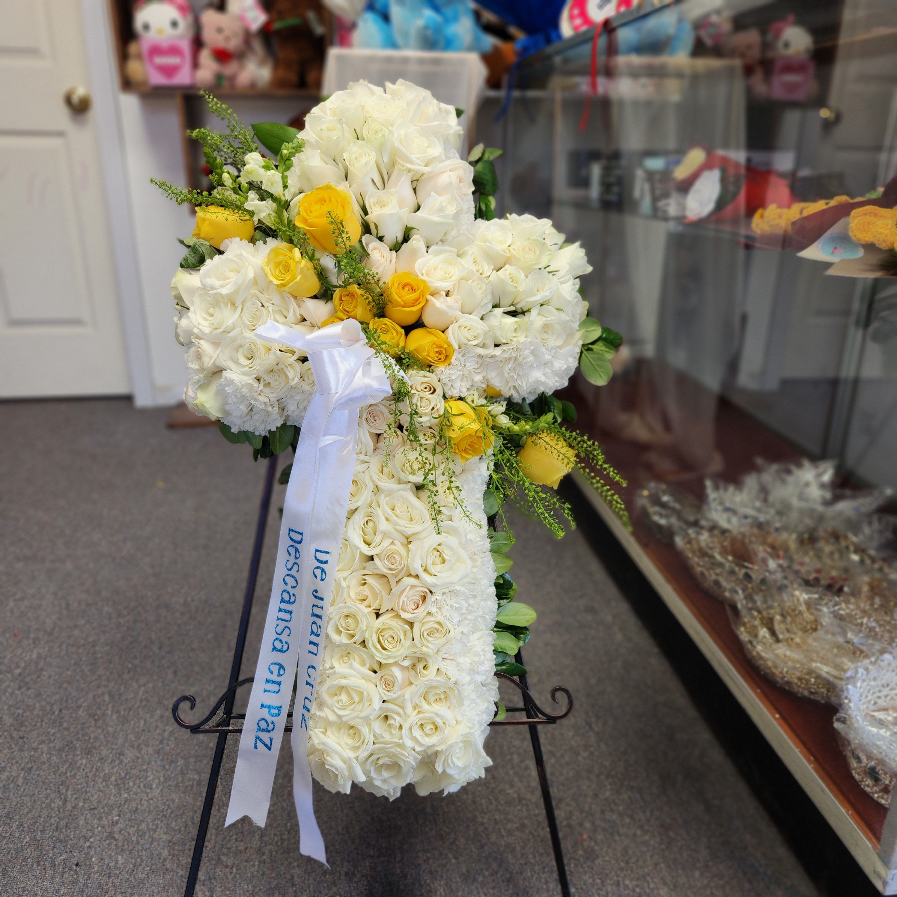 White and yellow rose arrangement on a stand with a ribbon