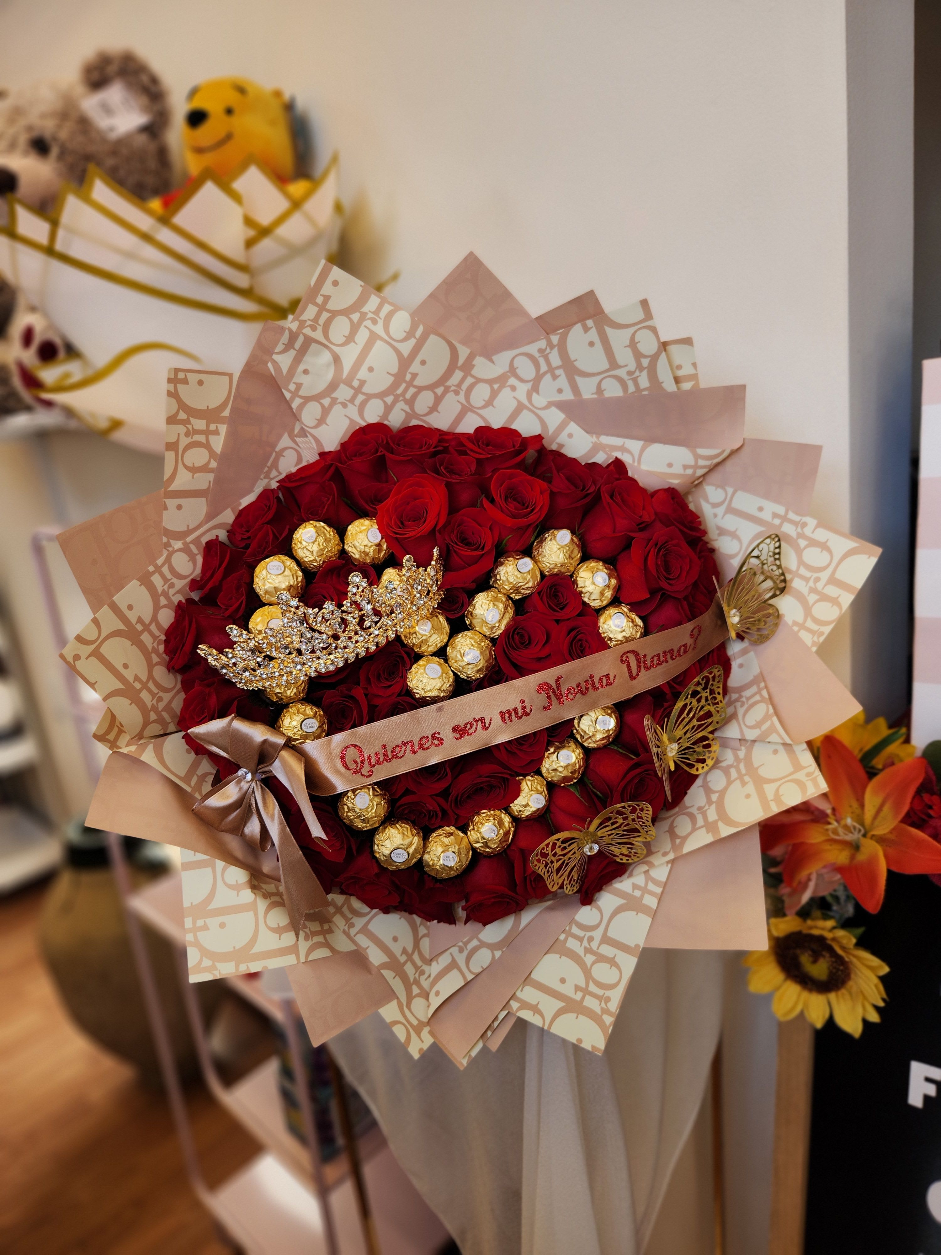 Bouquet of red roses with gold-wrapped chocolates and a decorative ribbon
