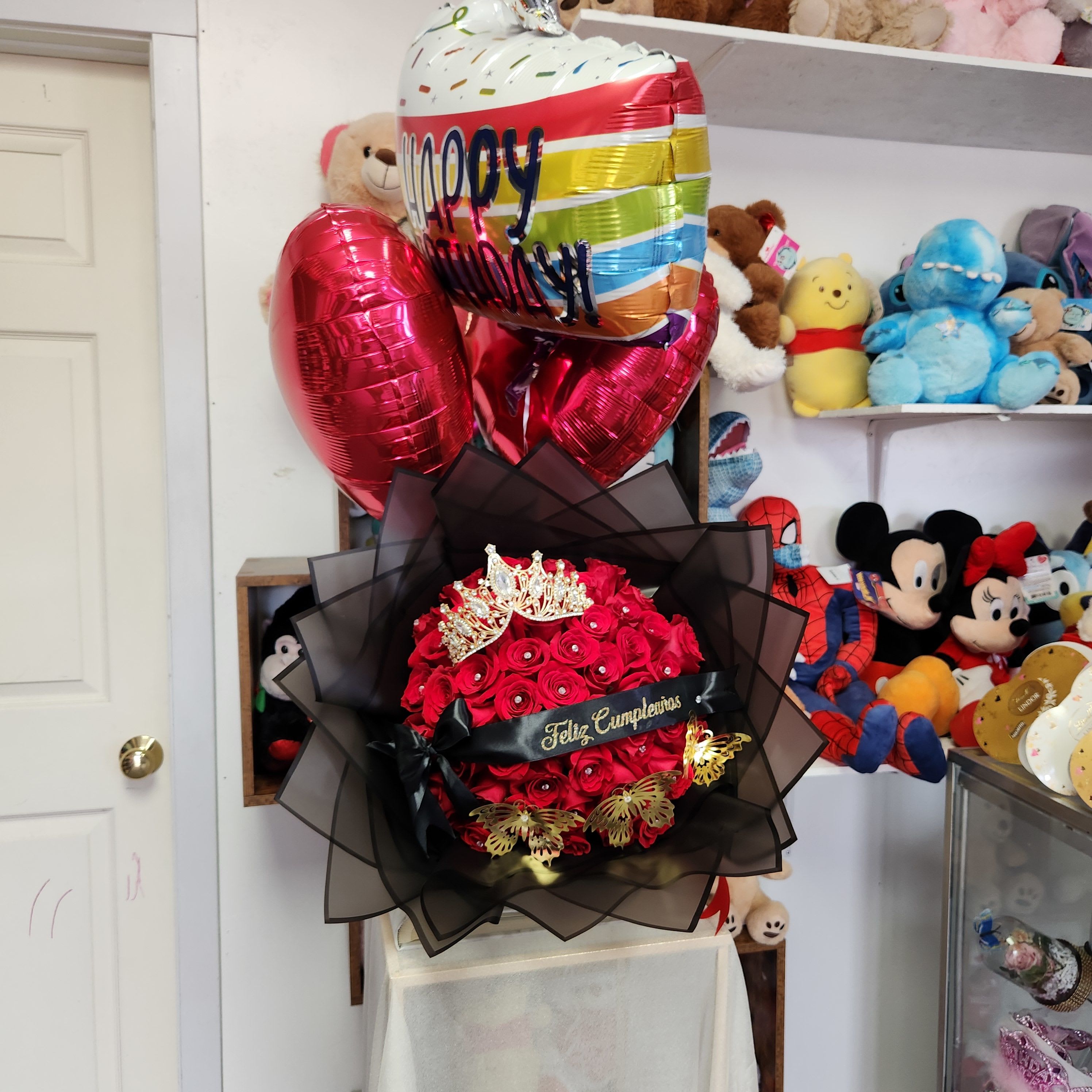 Red rose bouquet with a crown topper and birthday balloons