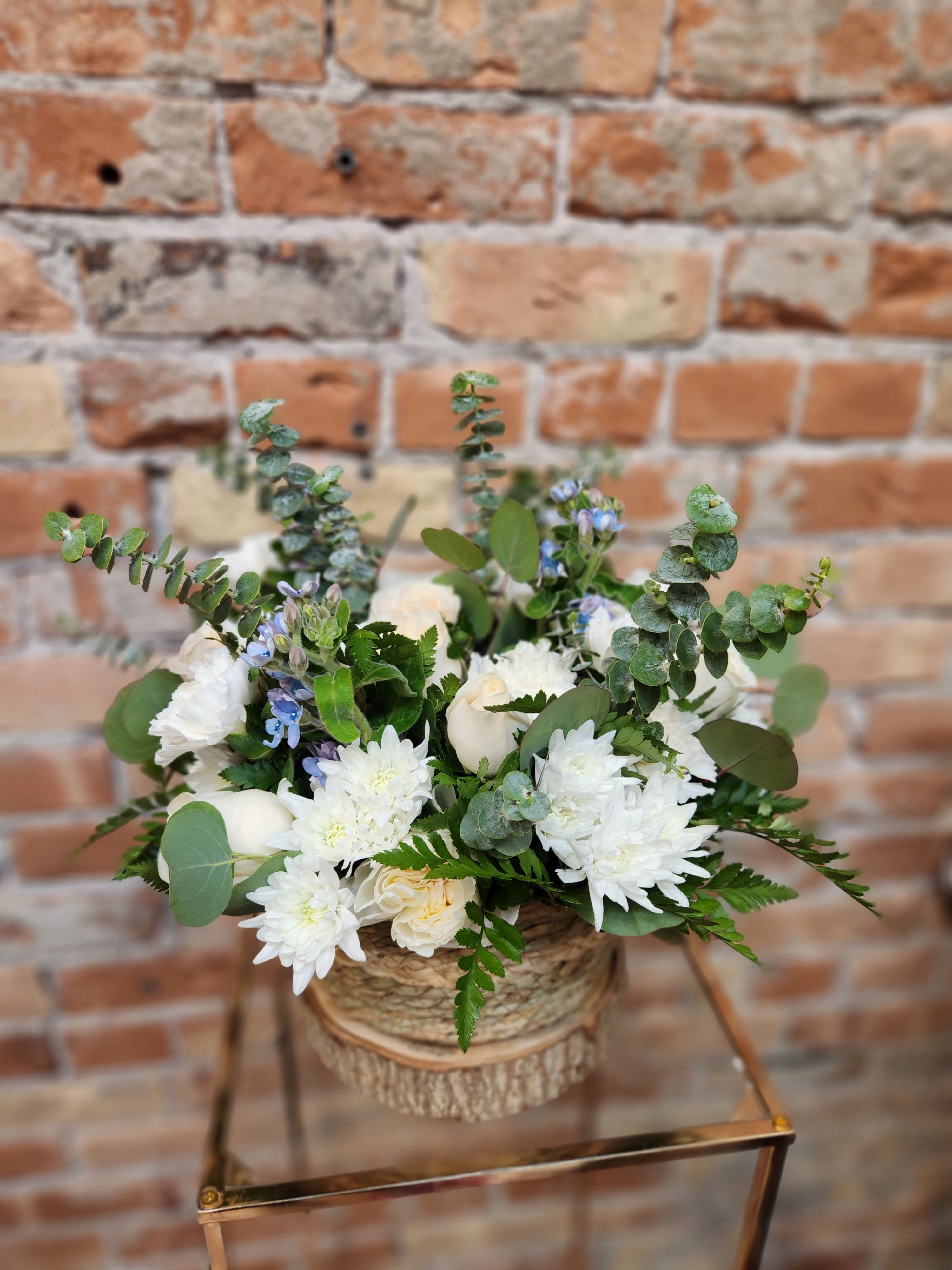 White floral arrangement in a woven basket with eucalyptus