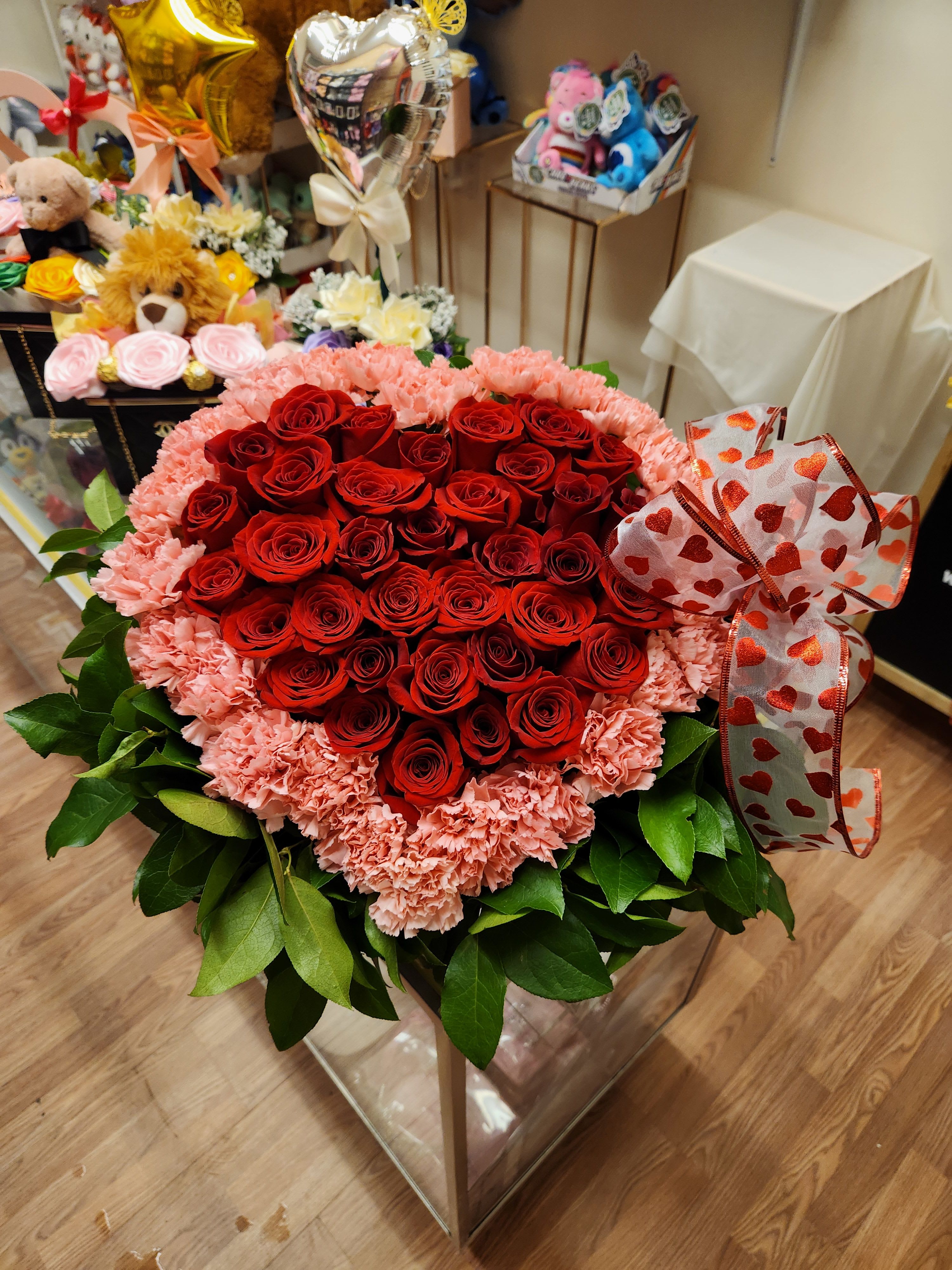 Heart-shaped bouquet of red roses and pink carnations with a heart ribbon