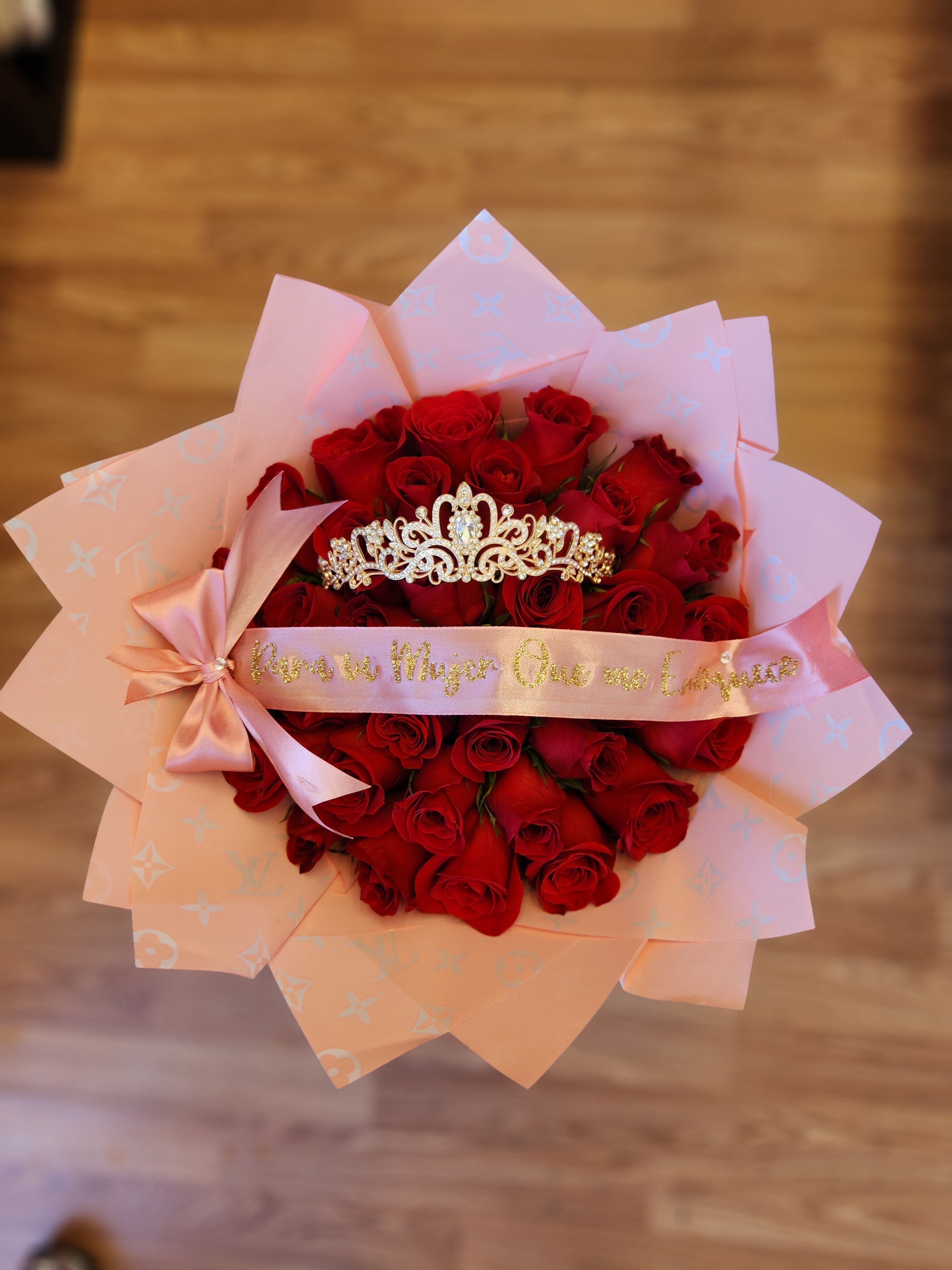 Bouquet of red roses wrapped in pink paper with a jeweled tiara