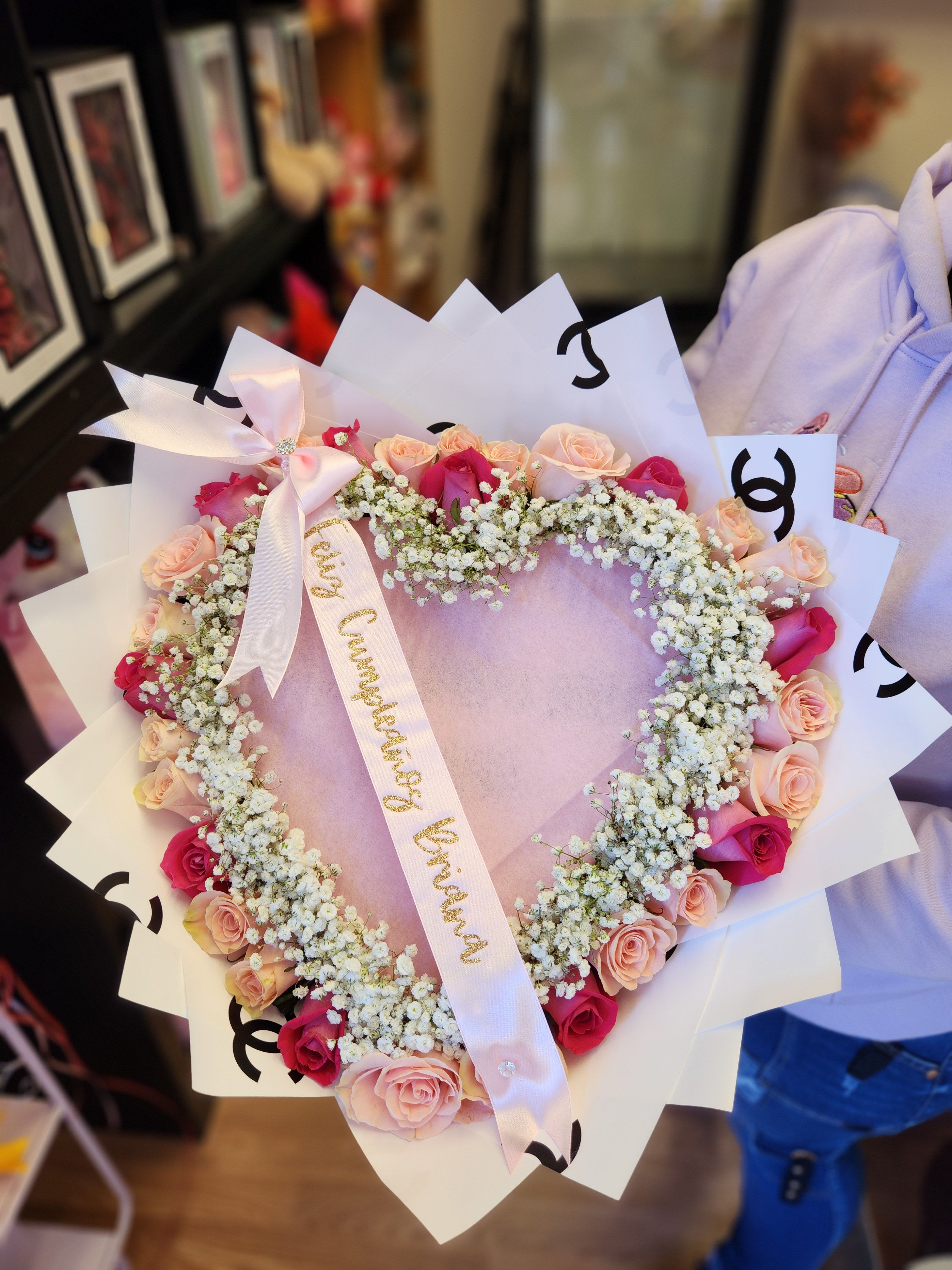 Heart-shaped bouquet of pink and peach roses with white baby's breath