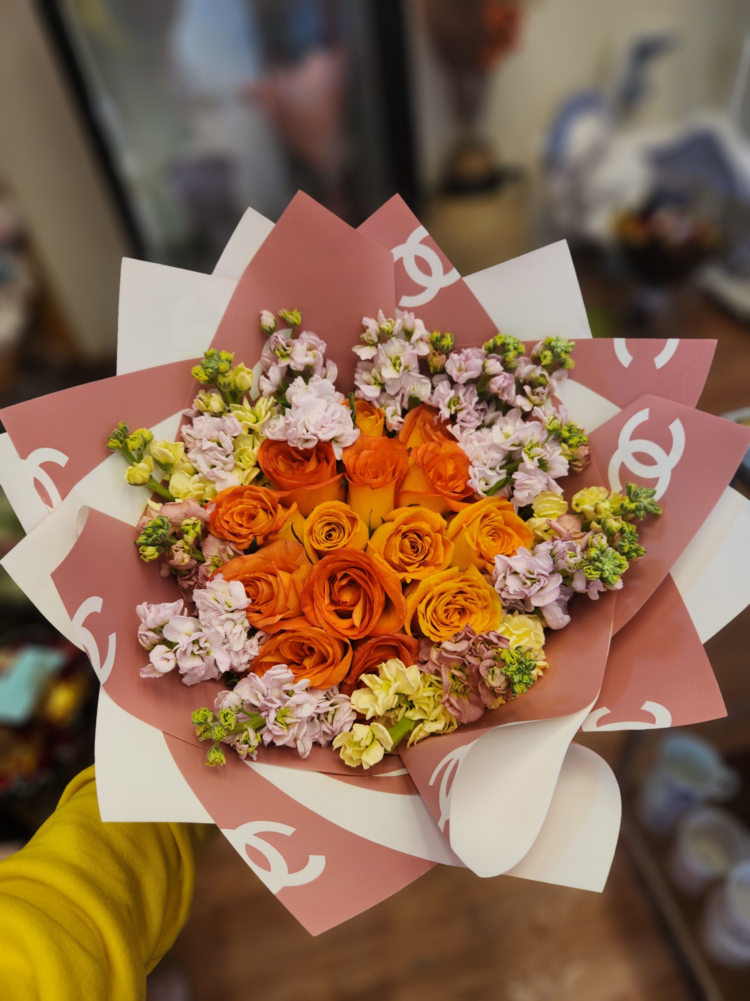 Bouquet of orange roses and pale pink flowers wrapped in pink and white paper
