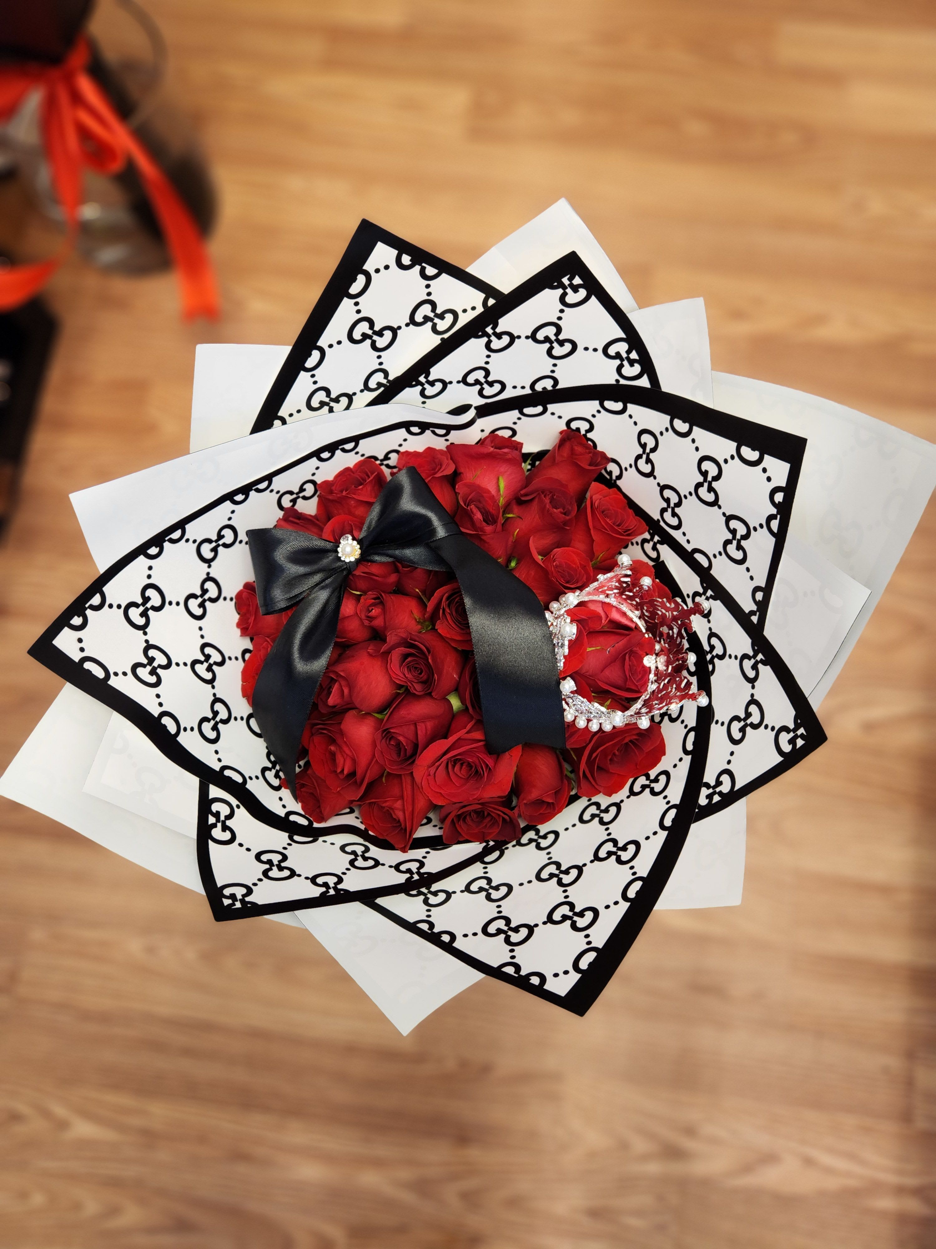 Bouquet of red roses wrapped in black-and-white patterned paper with a black ribbon