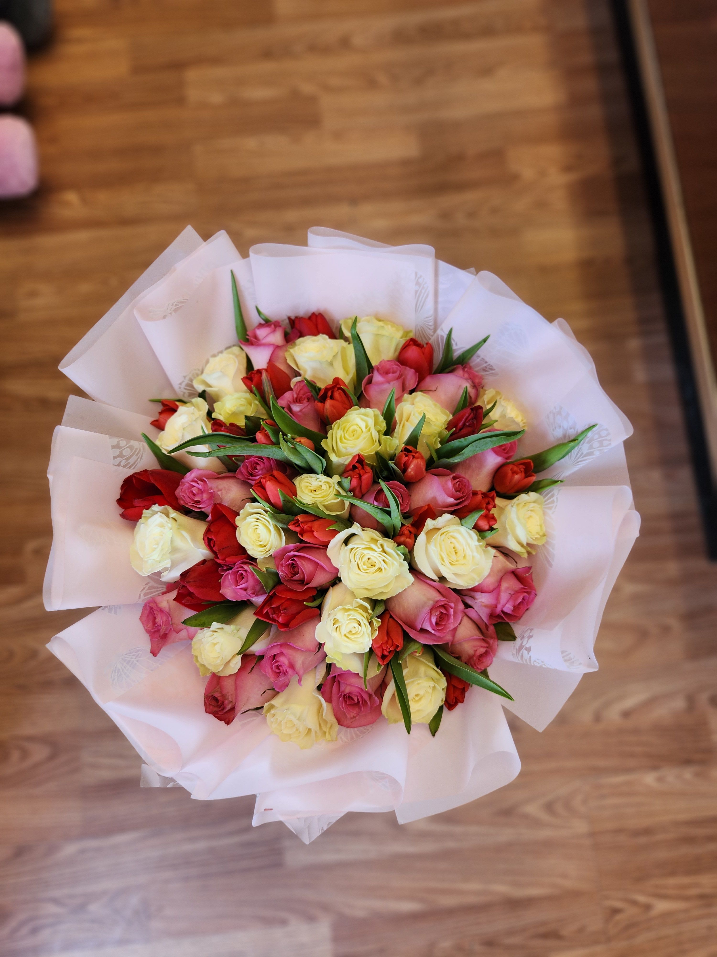 Bouquet of pink, red, and yellow roses wrapped in white paper