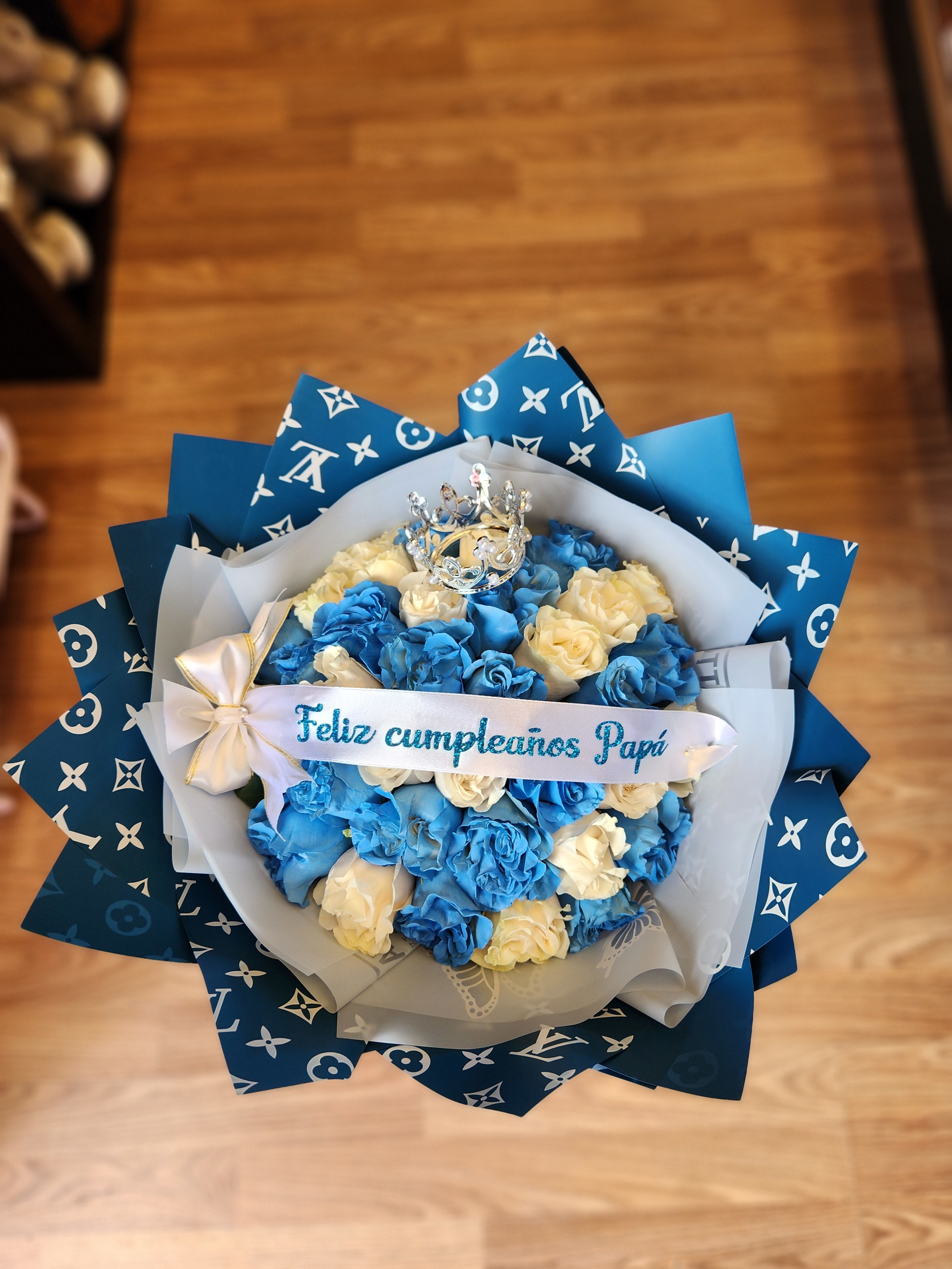 Blue and cream rose bouquet with a crown topper and birthday ribbon