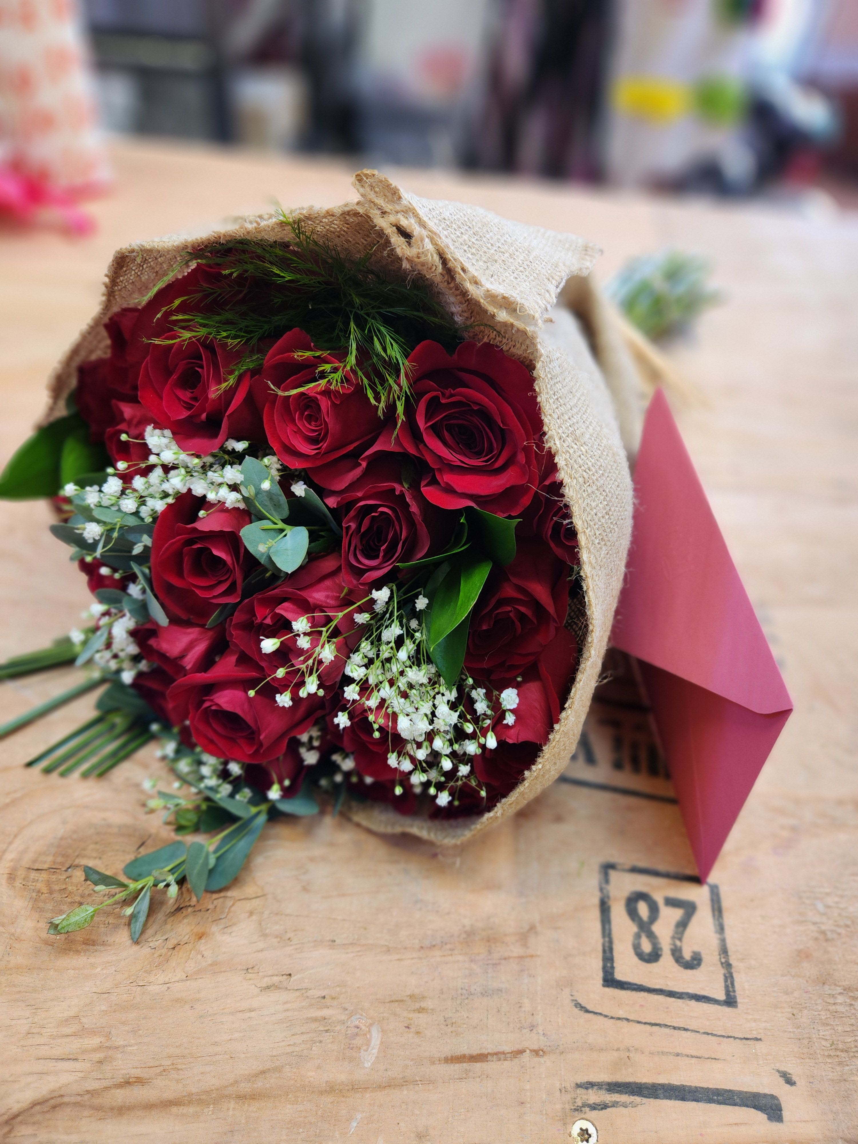 Bouquet of red roses wrapped in burlap with pink paper