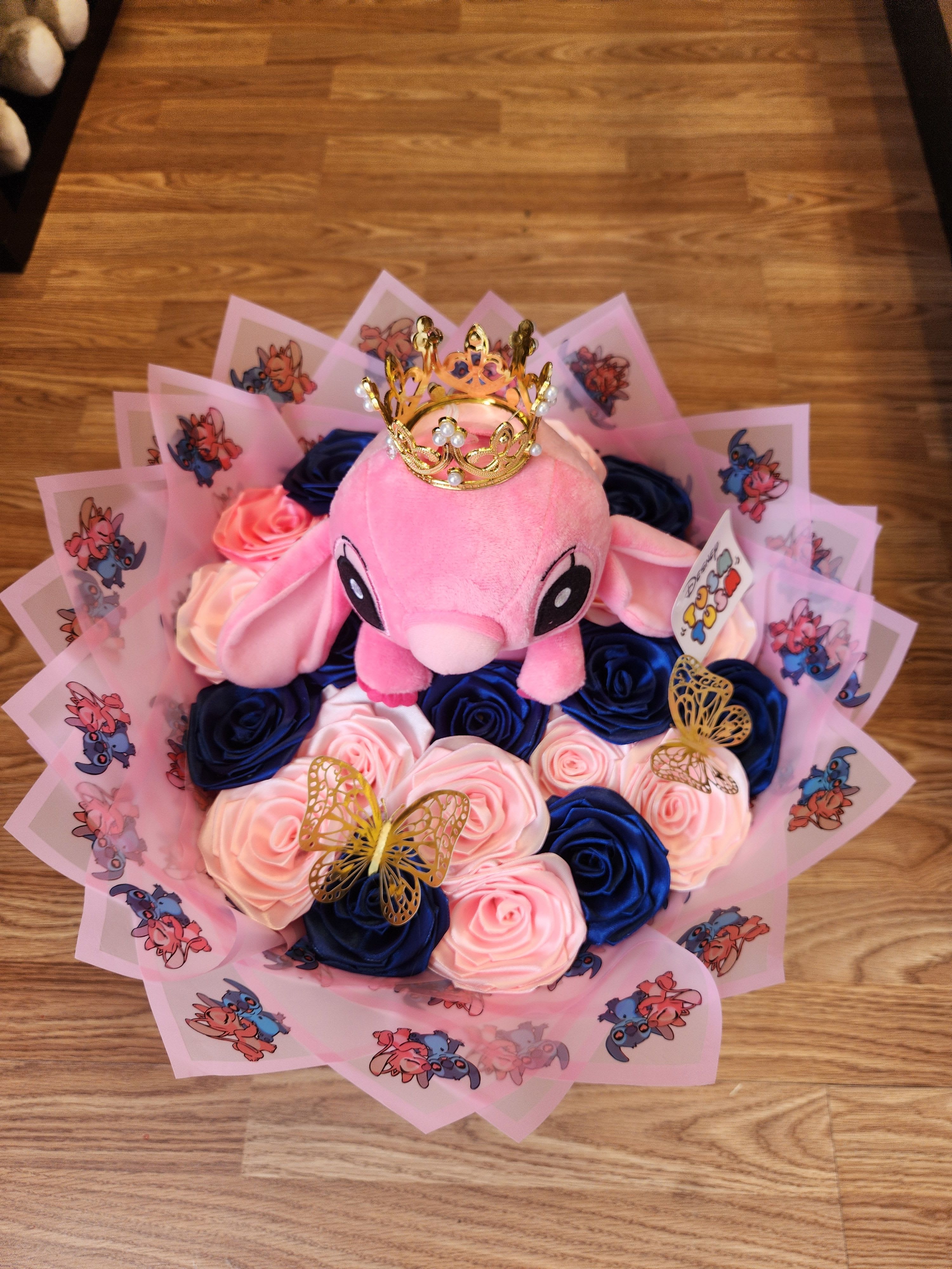 Pink plush toy surrounded by blue and pink roses with a gold crown