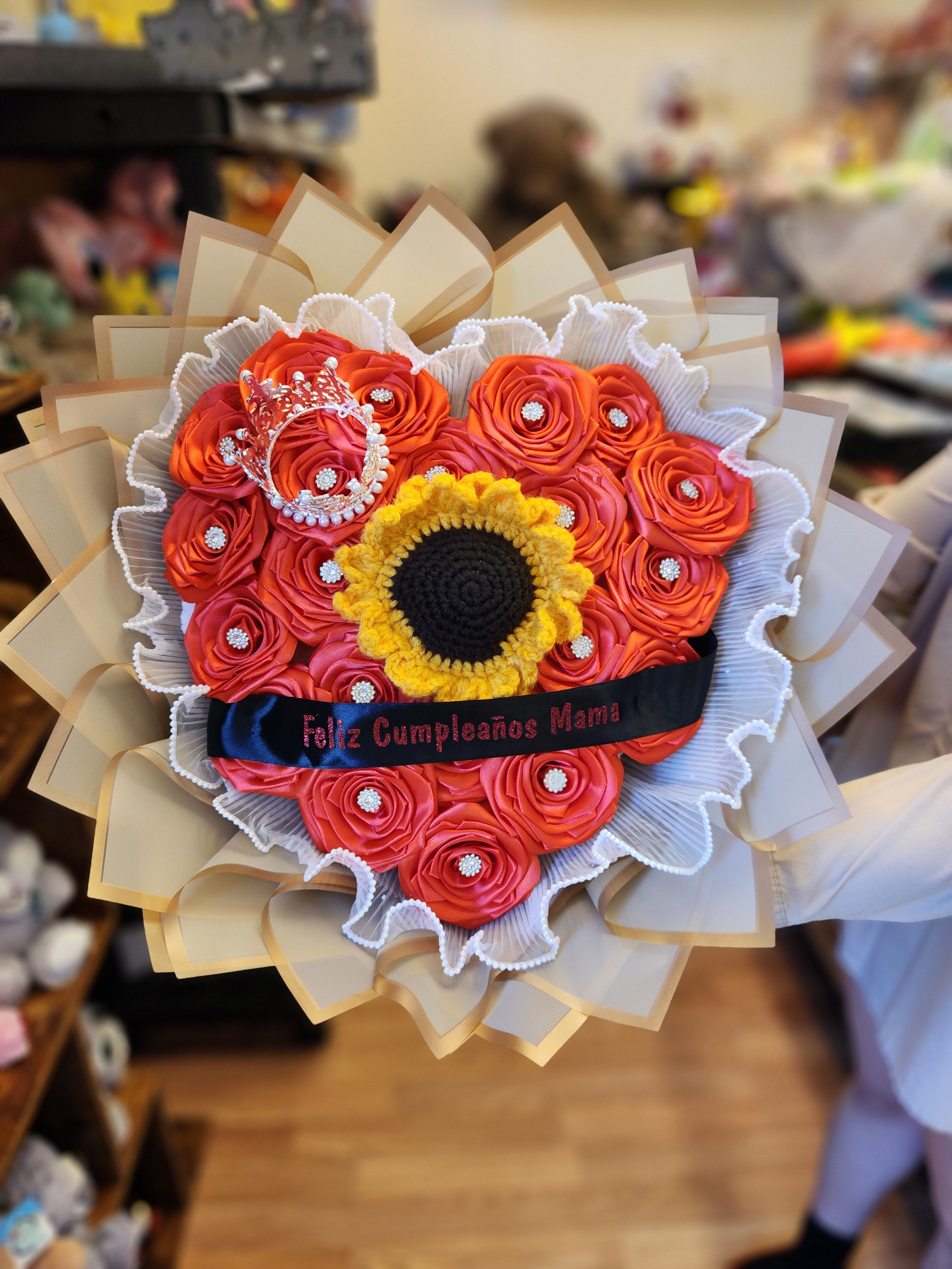 Bouquet of orange roses with a sunflower center and a crown topper