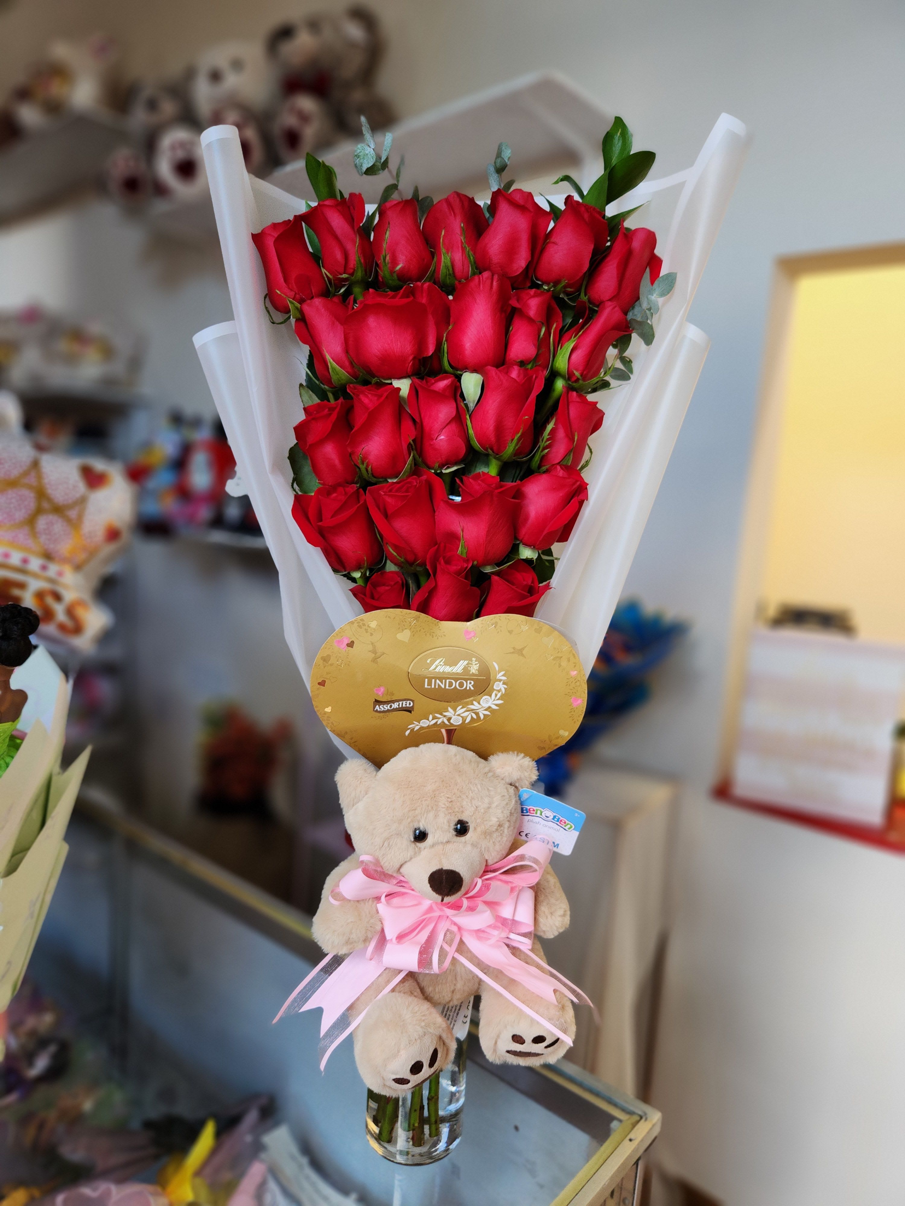 Bouquet of red roses with a teddy bear and chocolate gift topper