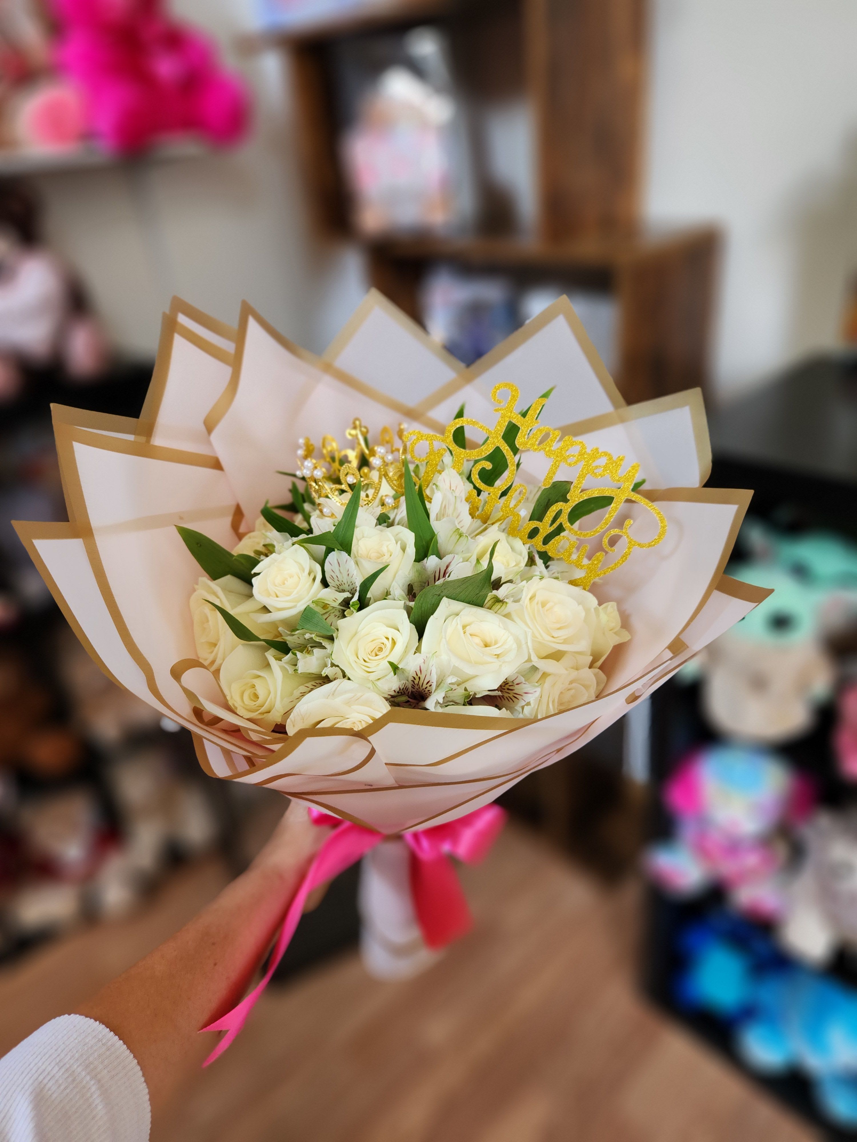 Bouquet of white roses with a gold "Happy Birthday" topper