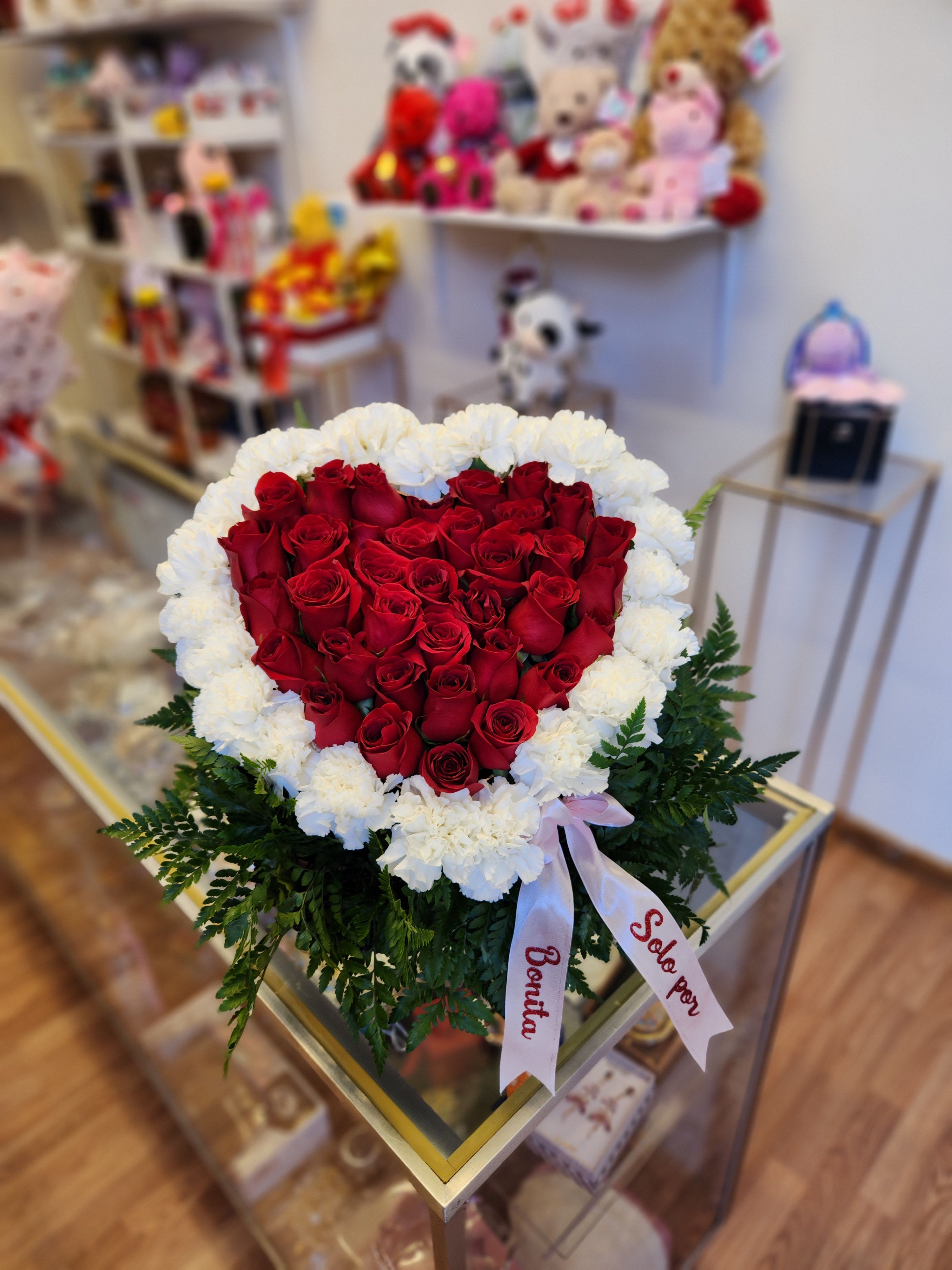 Heart-shaped bouquet of red roses edged with white carnations