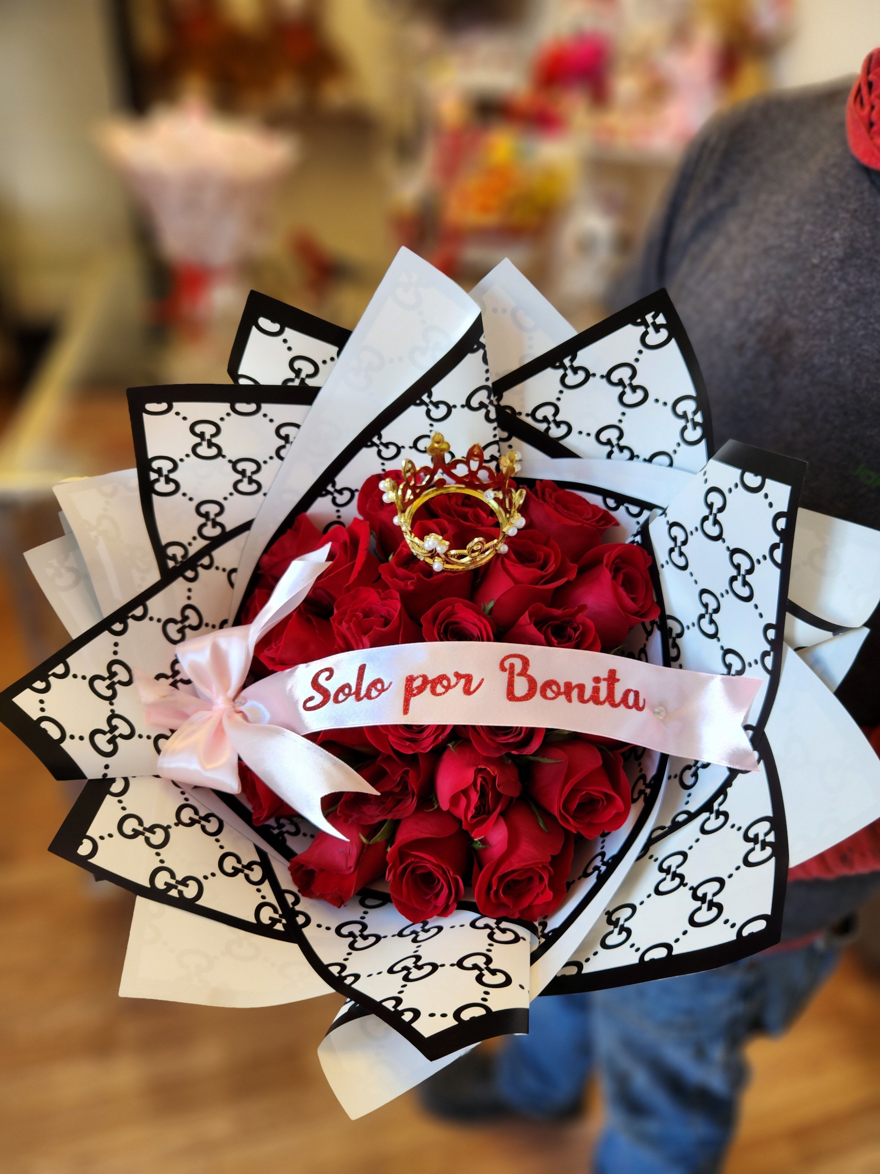 Bouquet of red roses wrapped in black-and-white patterned paper with a pink ribbon
