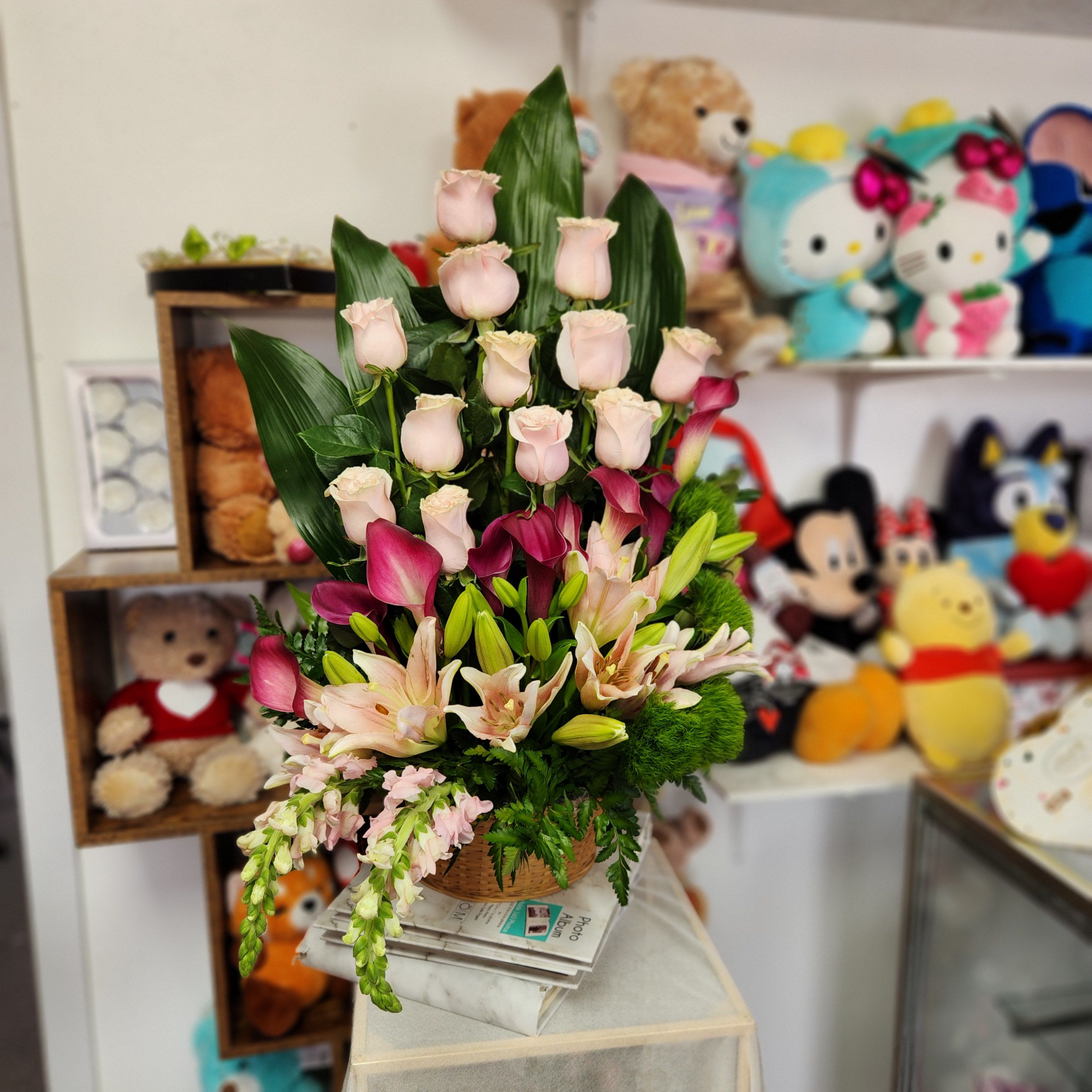 Mixed bouquet of pale pink roses, lilies, and calla lilies in a basket