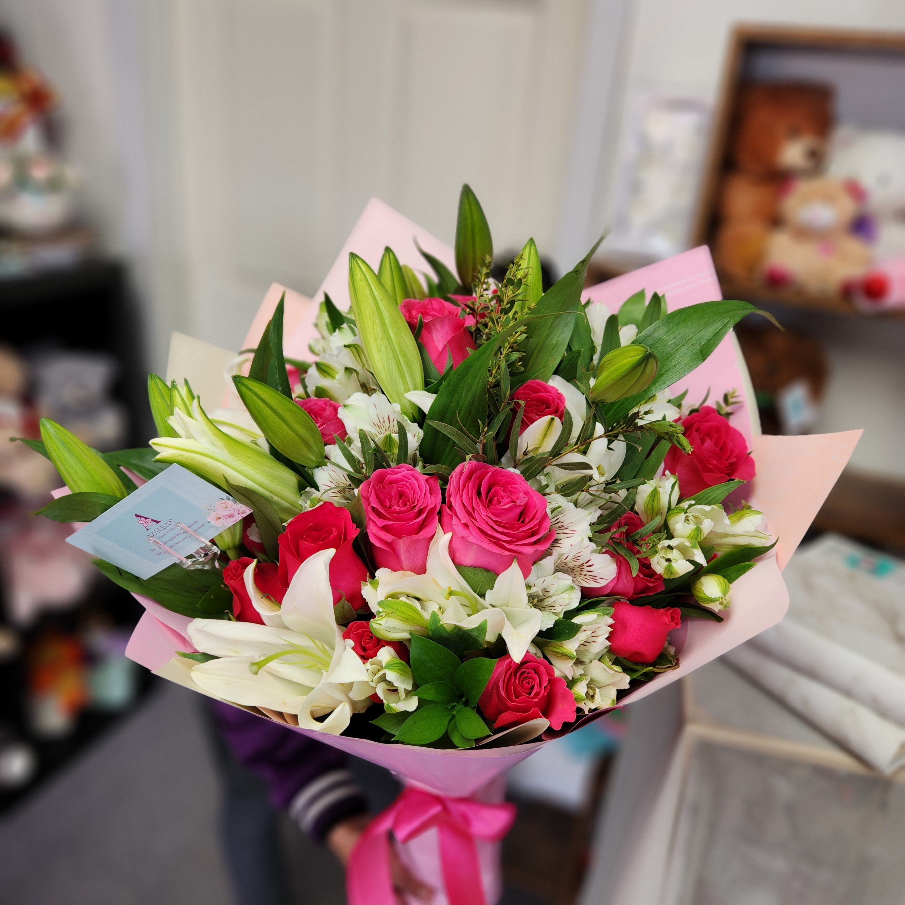 Bouquet of pink roses and white lilies wrapped in pink paper