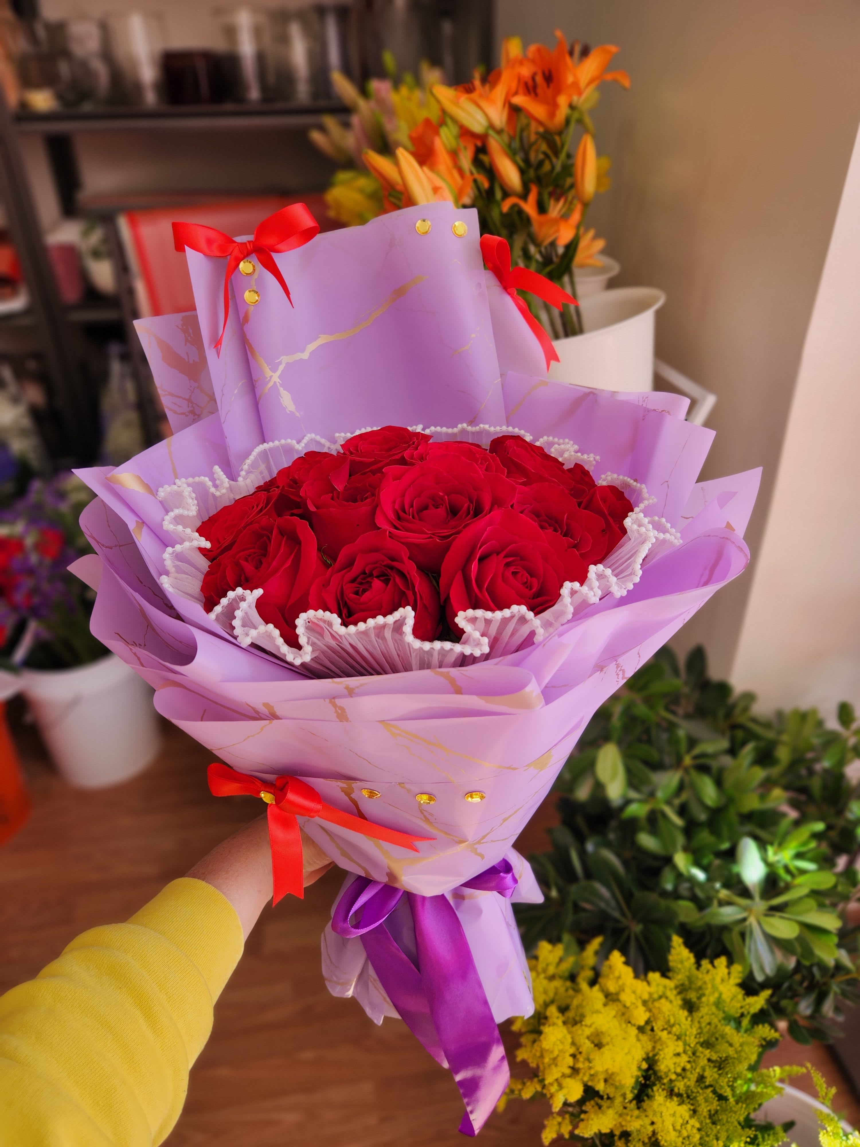 Bouquet of red roses wrapped in lavender paper with red ribbons
