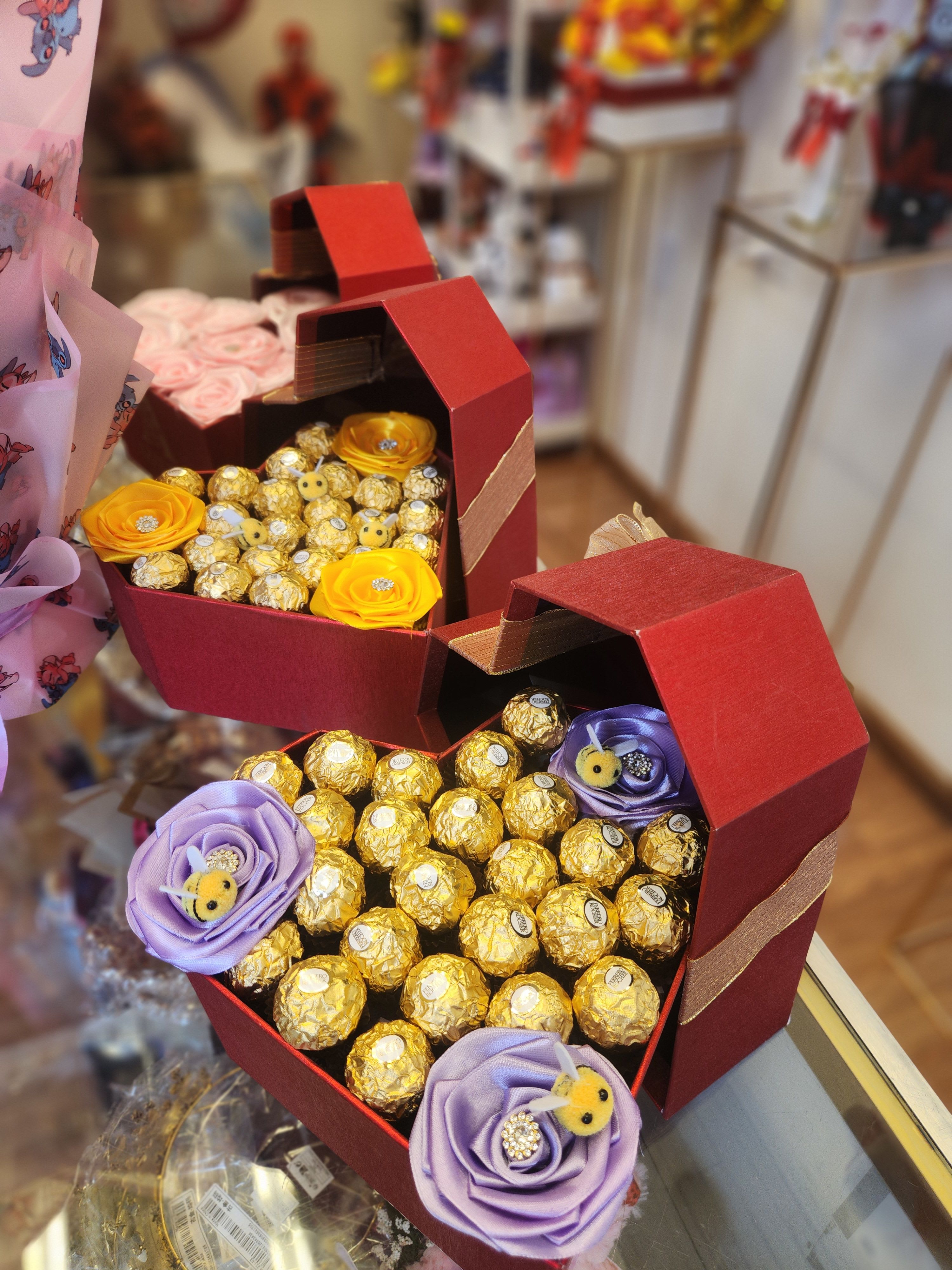 Heart-shaped gift boxes filled with chocolates and ribbon flowers