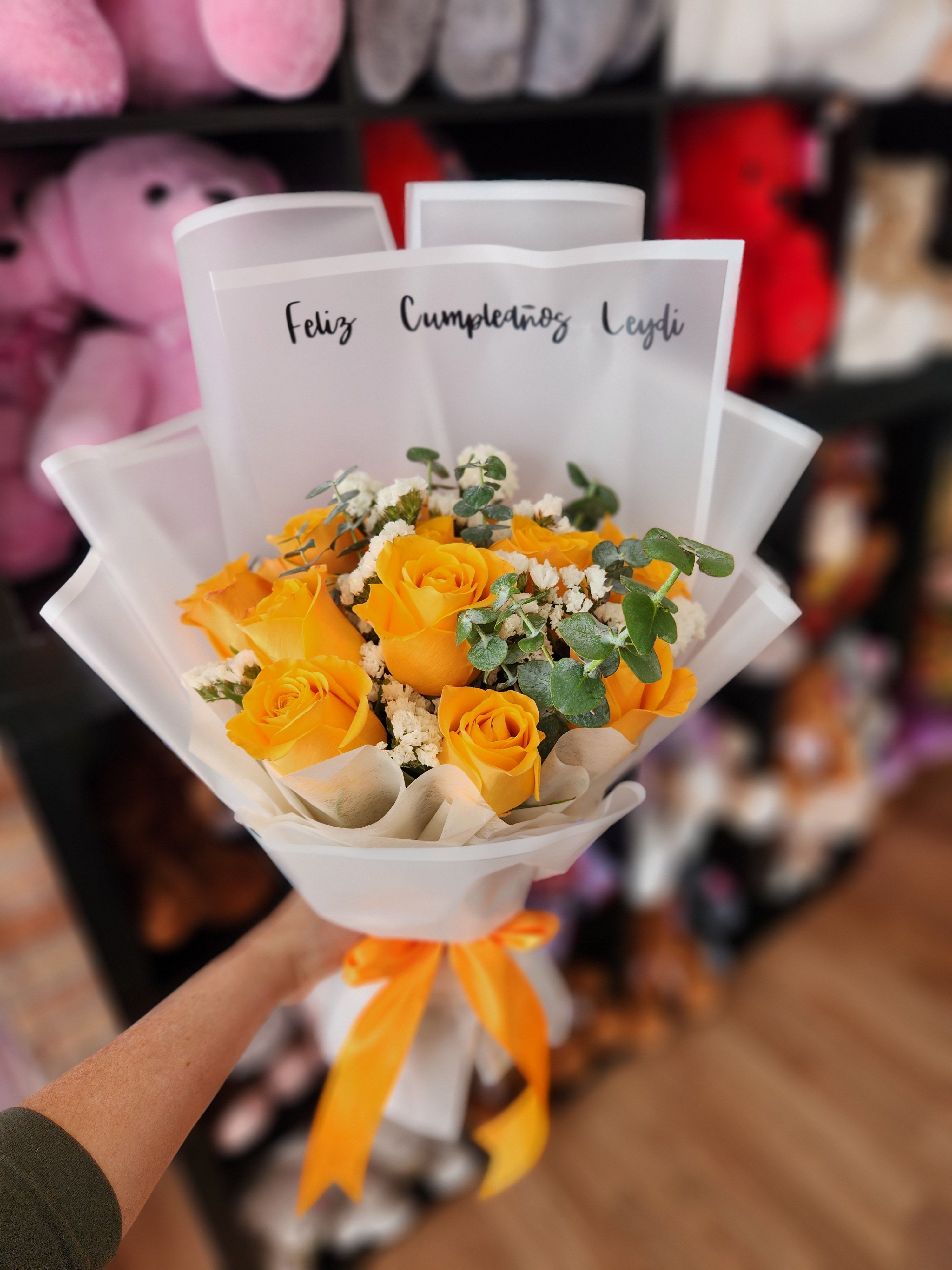Bouquet of yellow roses wrapped in white paper with an orange ribbon