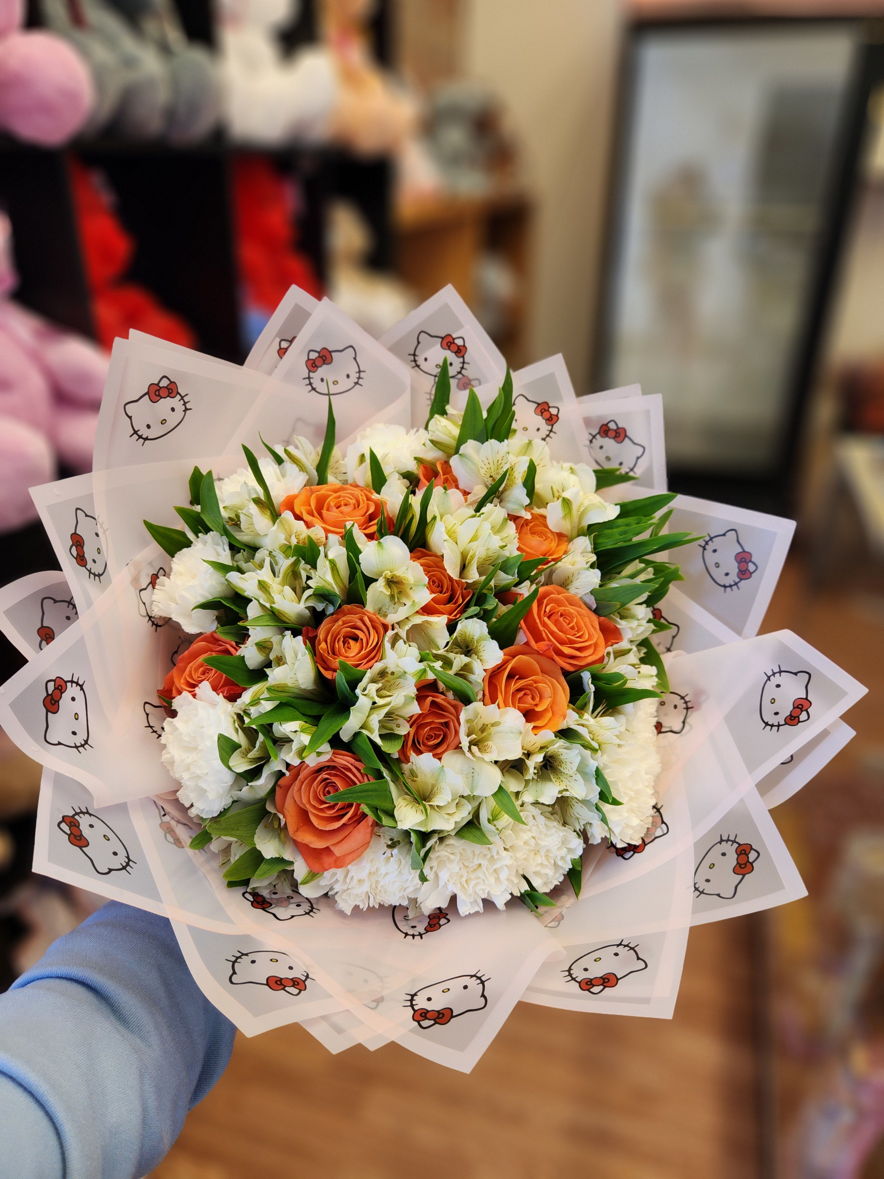 Orange roses and white flowers in Hello Kitty wrapping