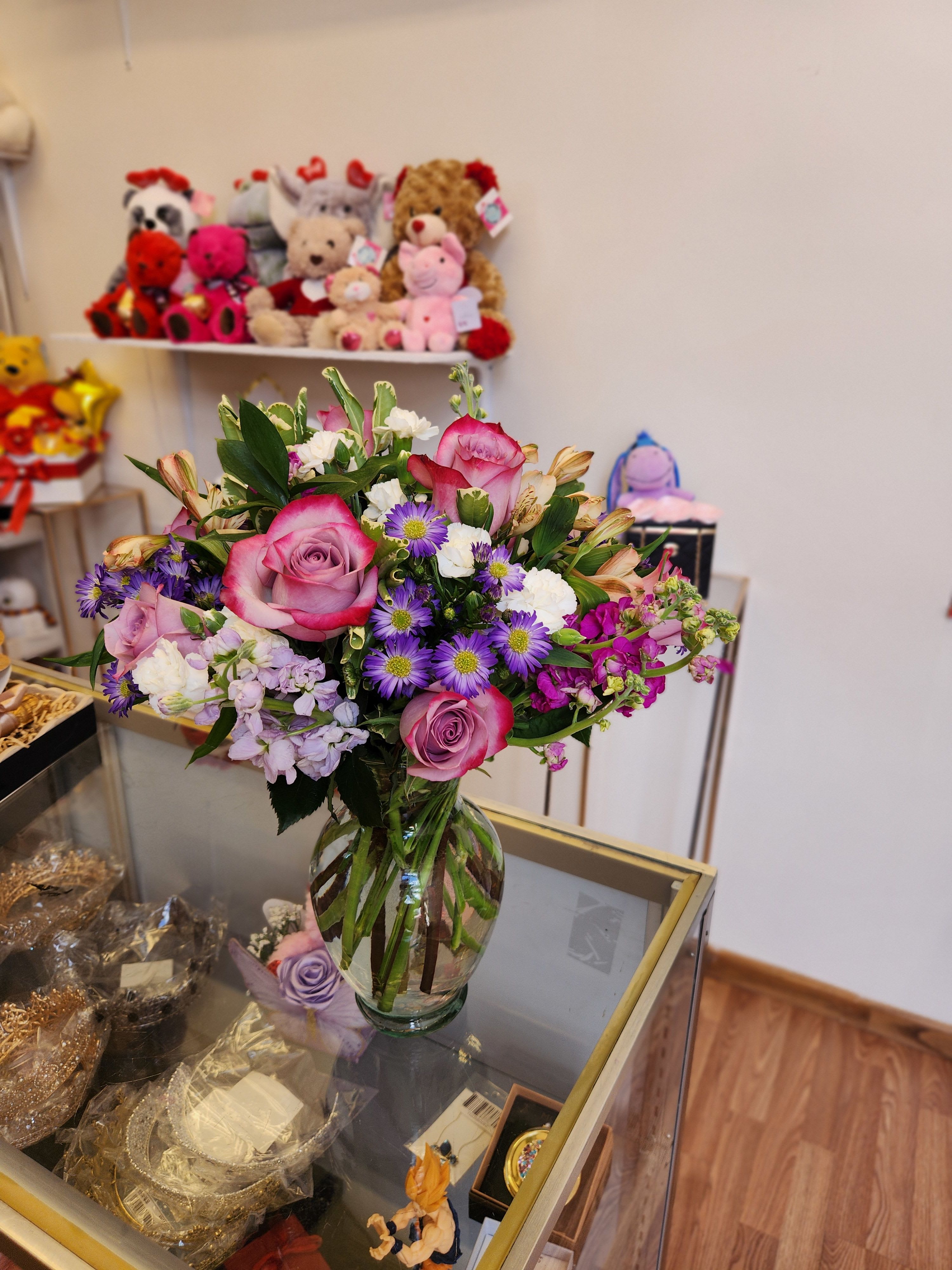 Mixed bouquet of pink roses and purple daisies in a glass vase