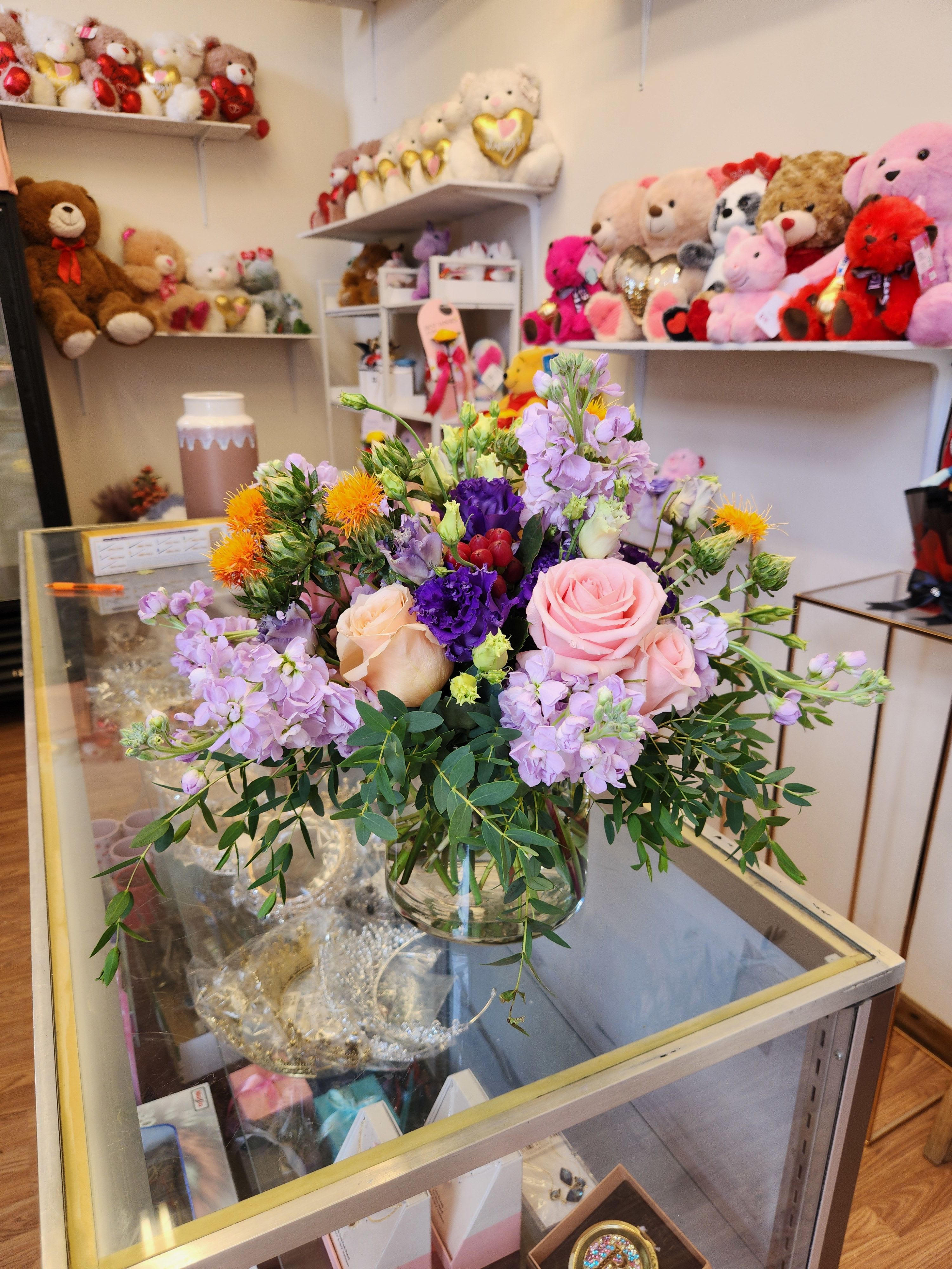 Mixed bouquet of pink, purple, and peach flowers in a glass vase