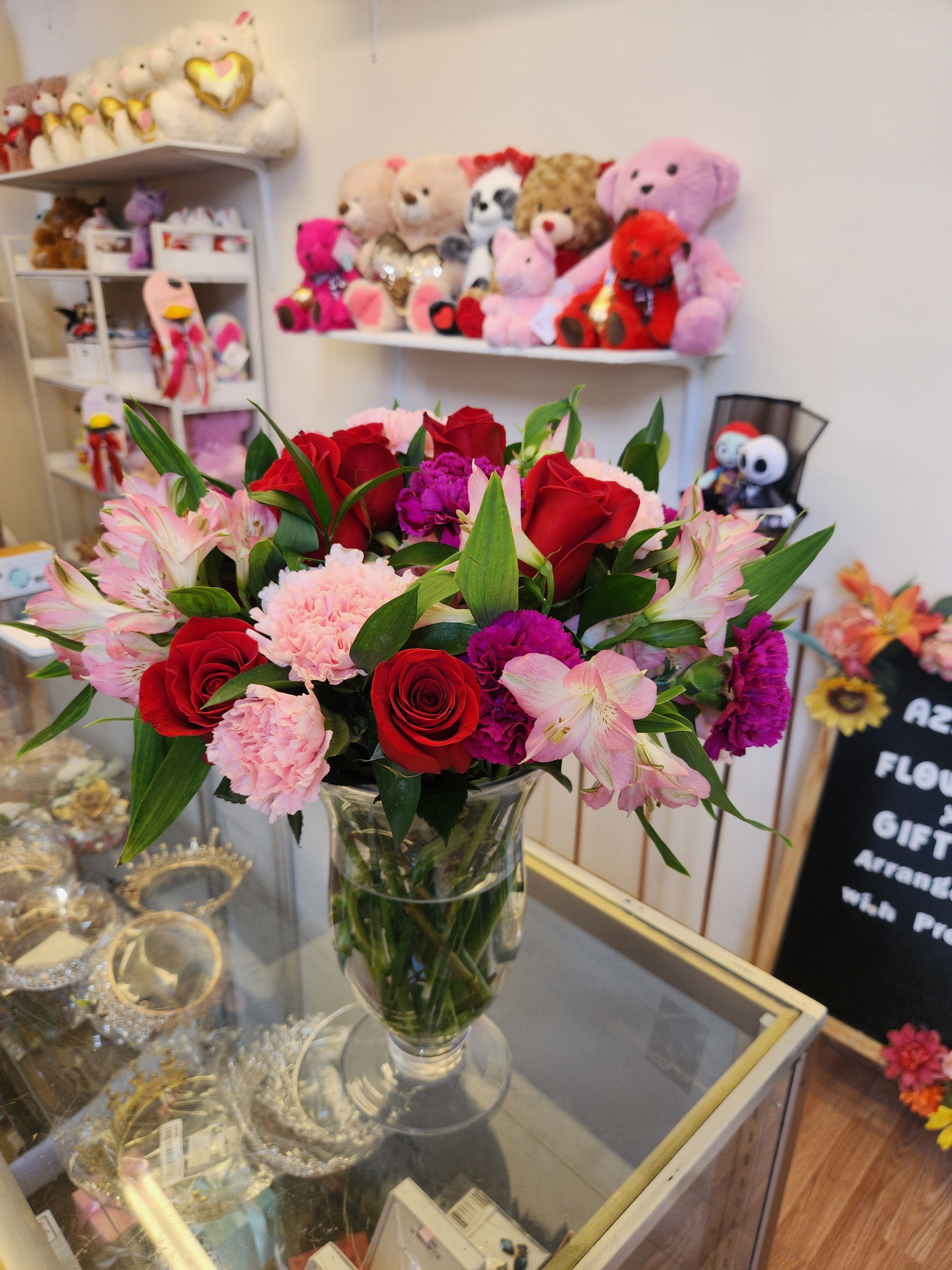 Bouquet of red roses, pink alstroemeria, and carnations in a clear glass vase