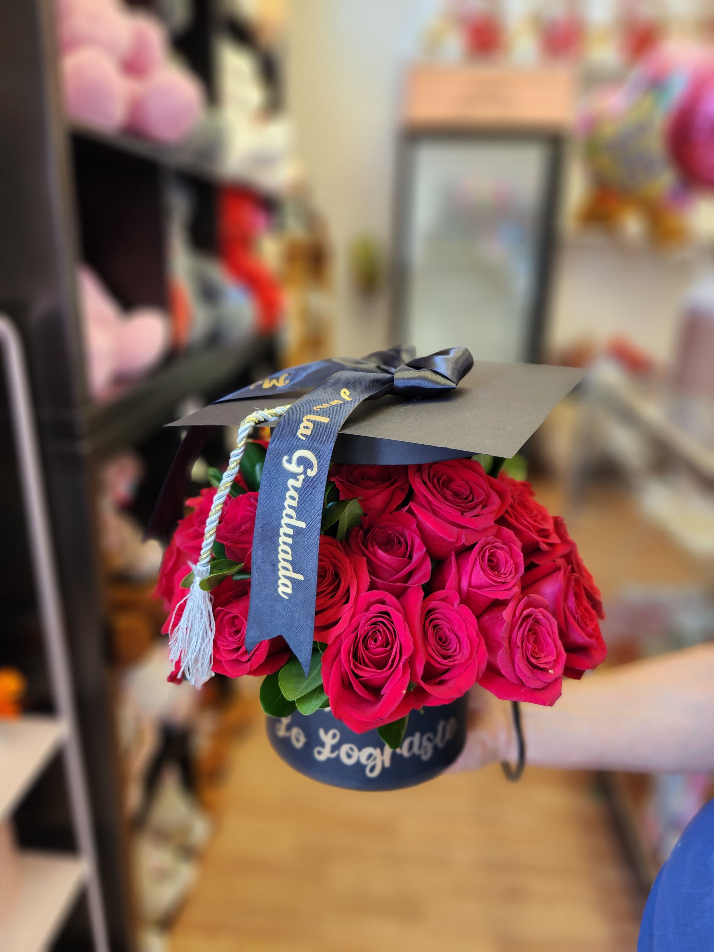 Bouquet of hot pink roses in a black hat box with a graduation ribbon
