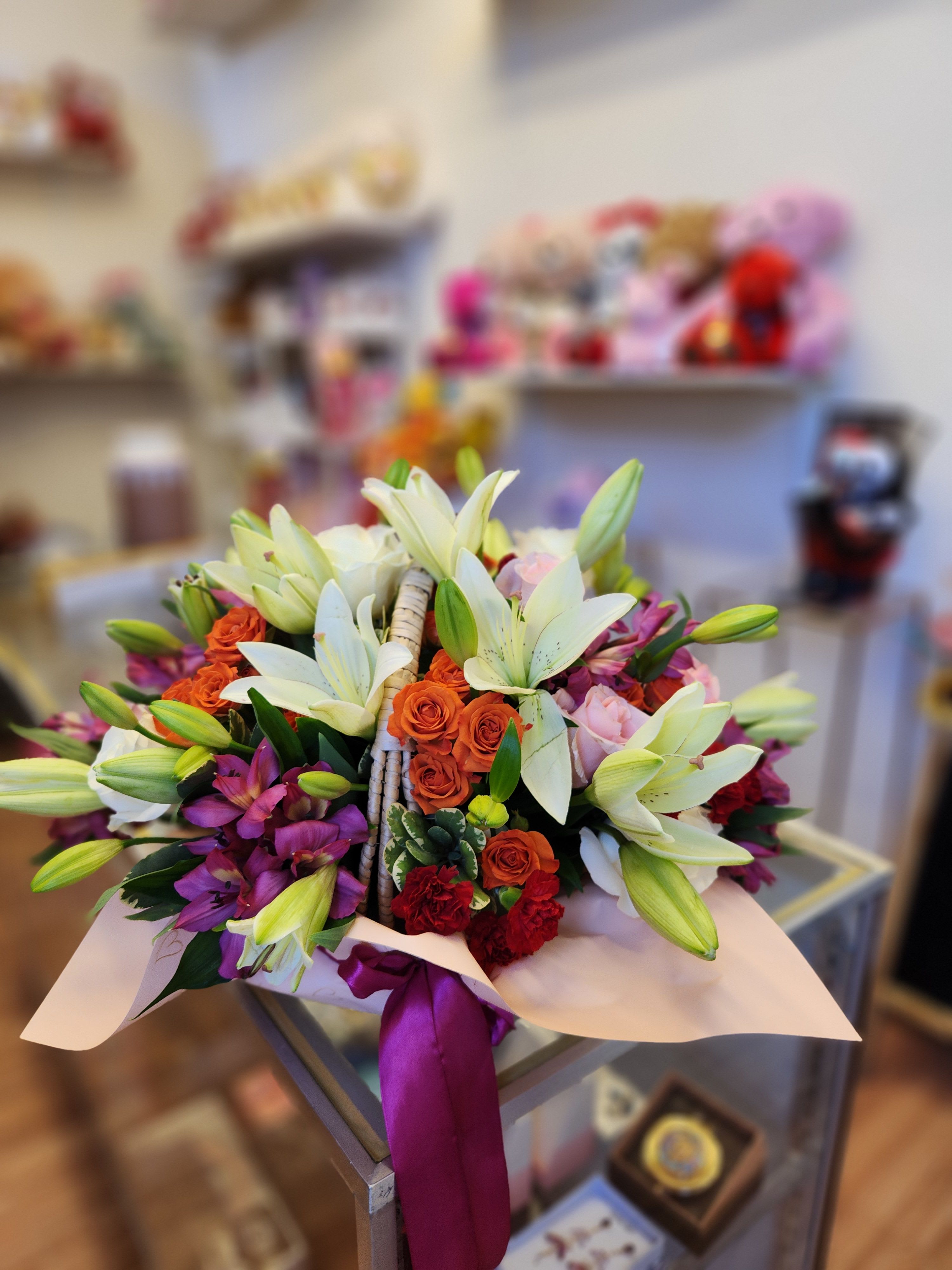 Bouquet of white lilies, orange roses, and purple orchids wrapped with ribbon
