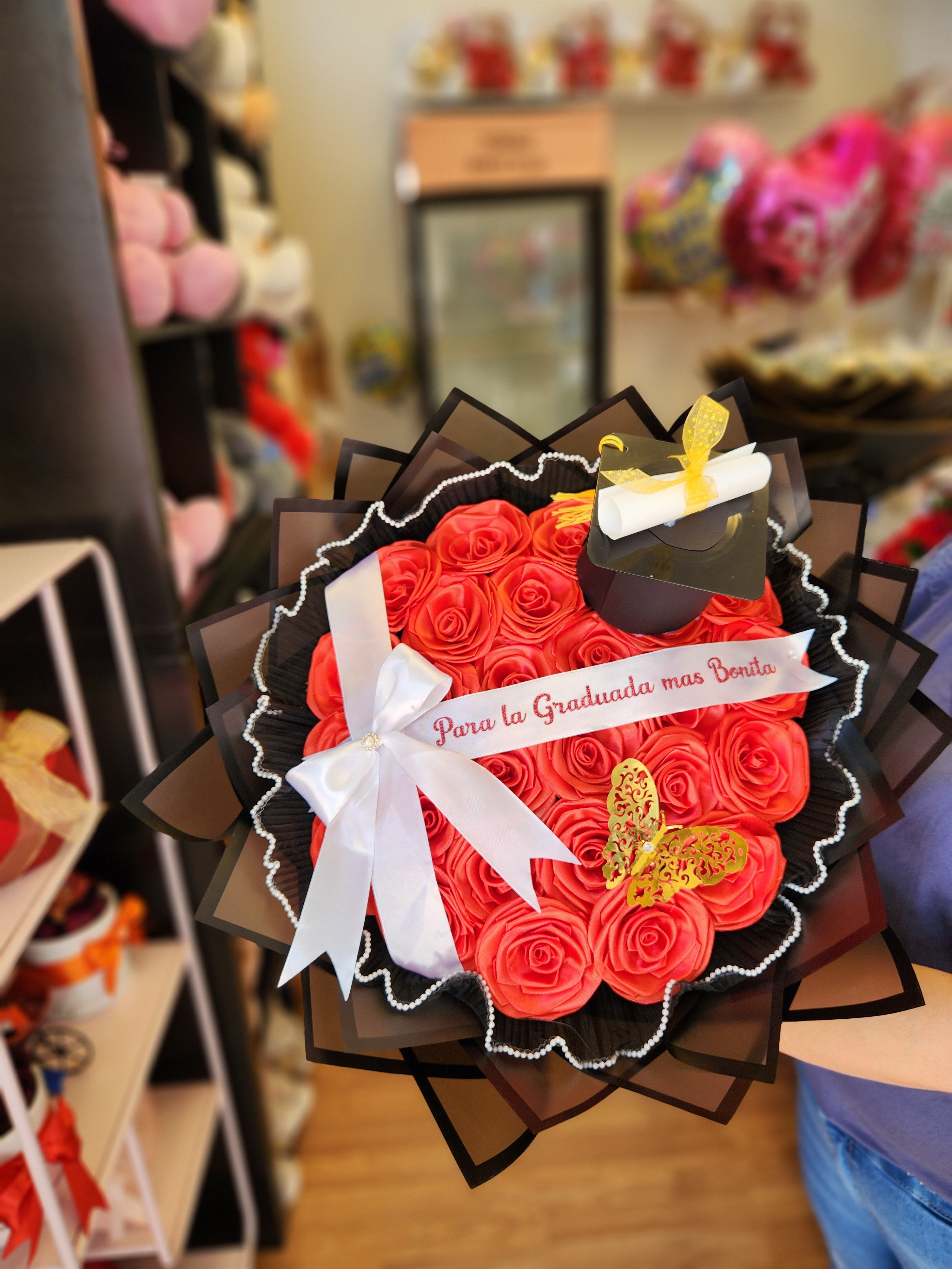 Bouquet of red roses with a graduation cap decoration and white ribbon