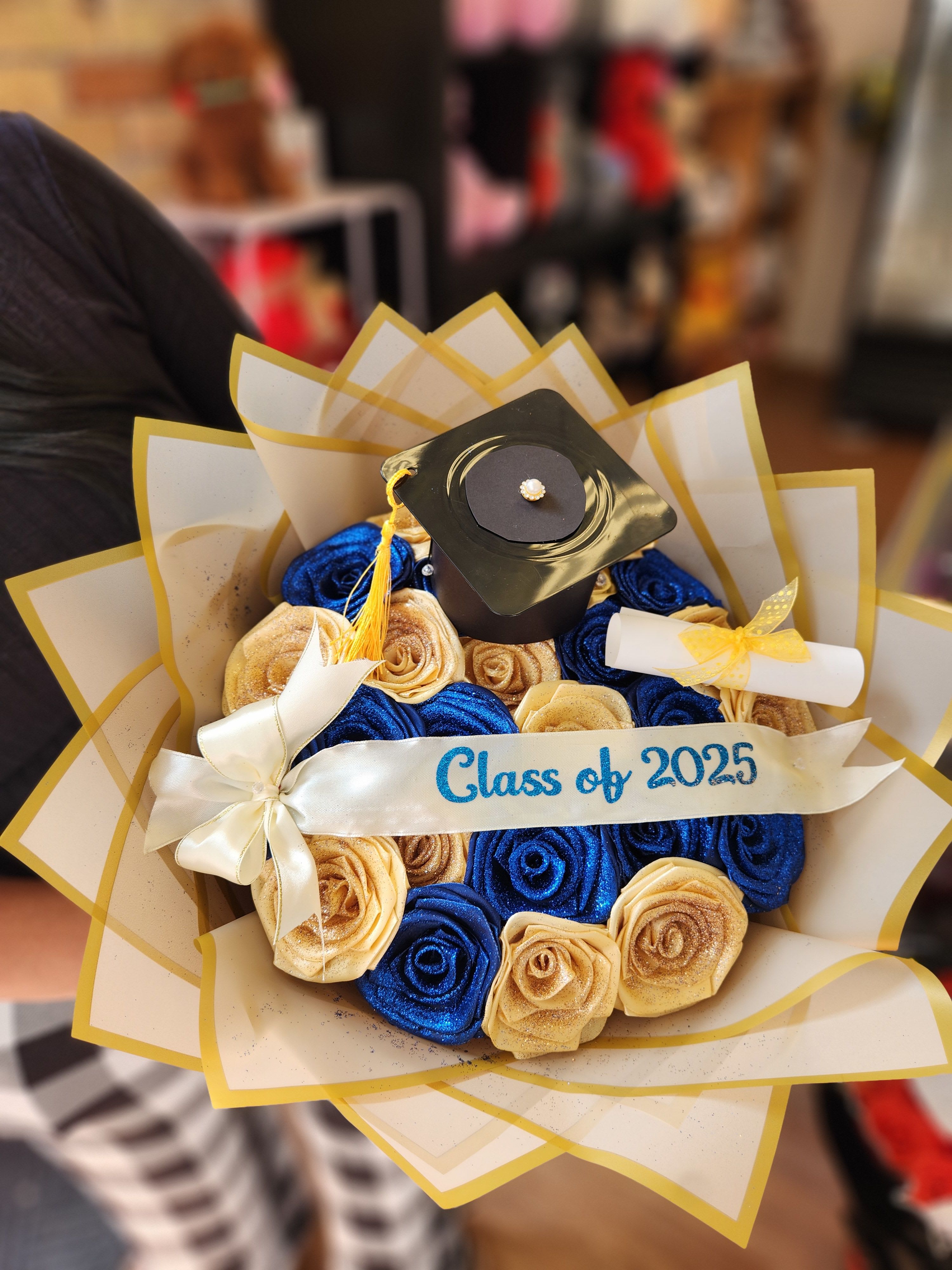 Graduation bouquet with blue and gold roses and a cap topper