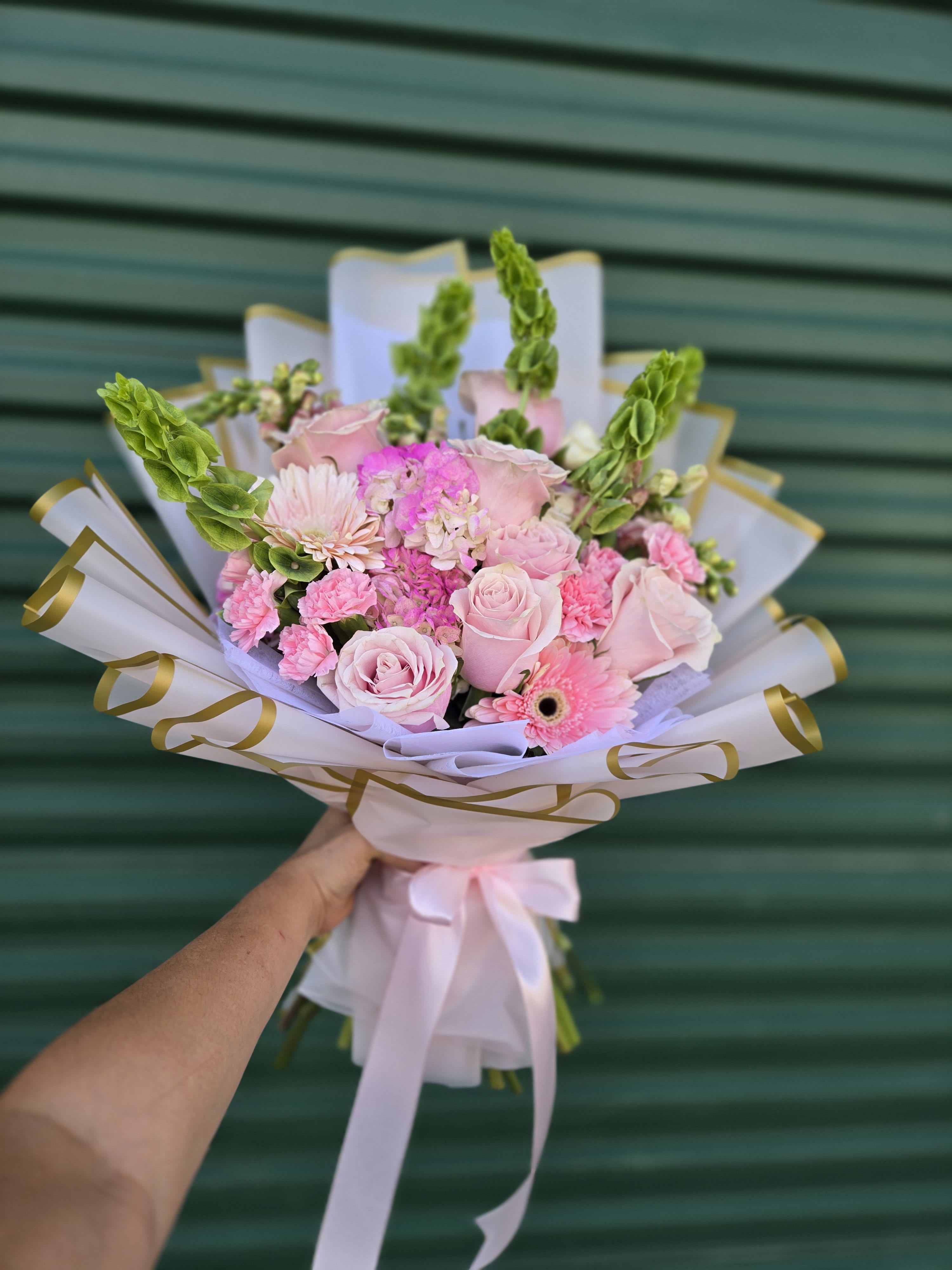 Pink rose bouquet with gerbera daisies and carnations wrapped in white paper