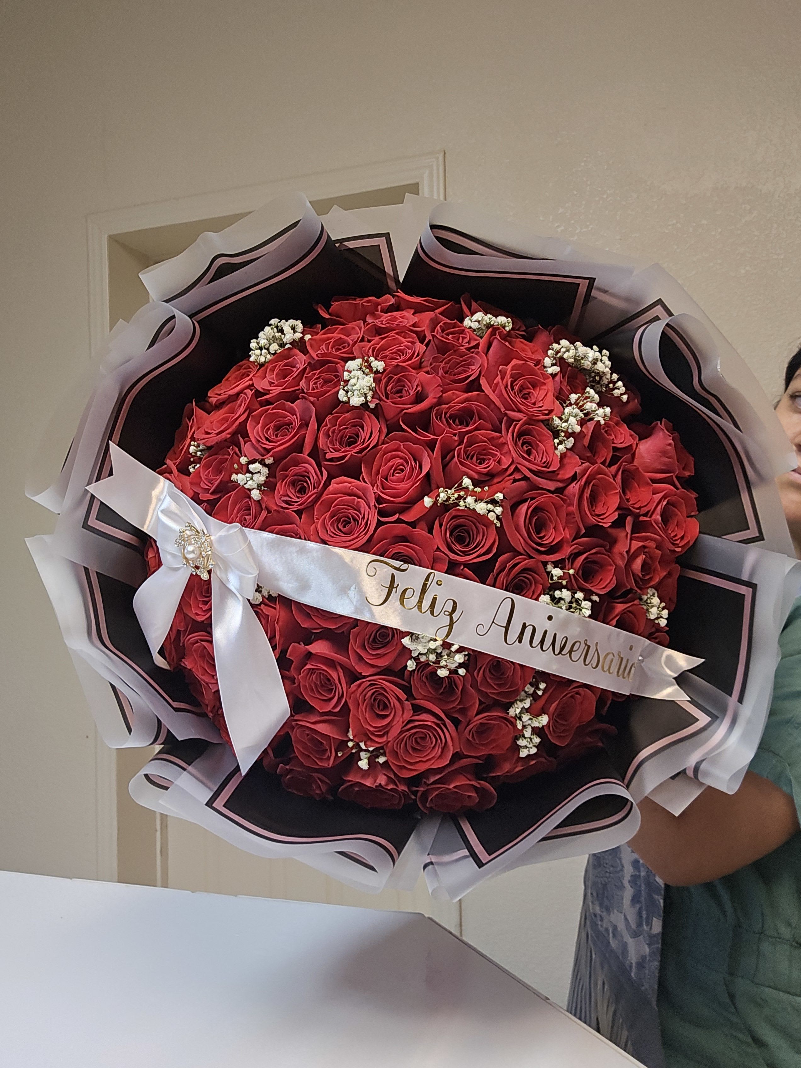 Large bouquet of red roses with a white anniversary ribbon