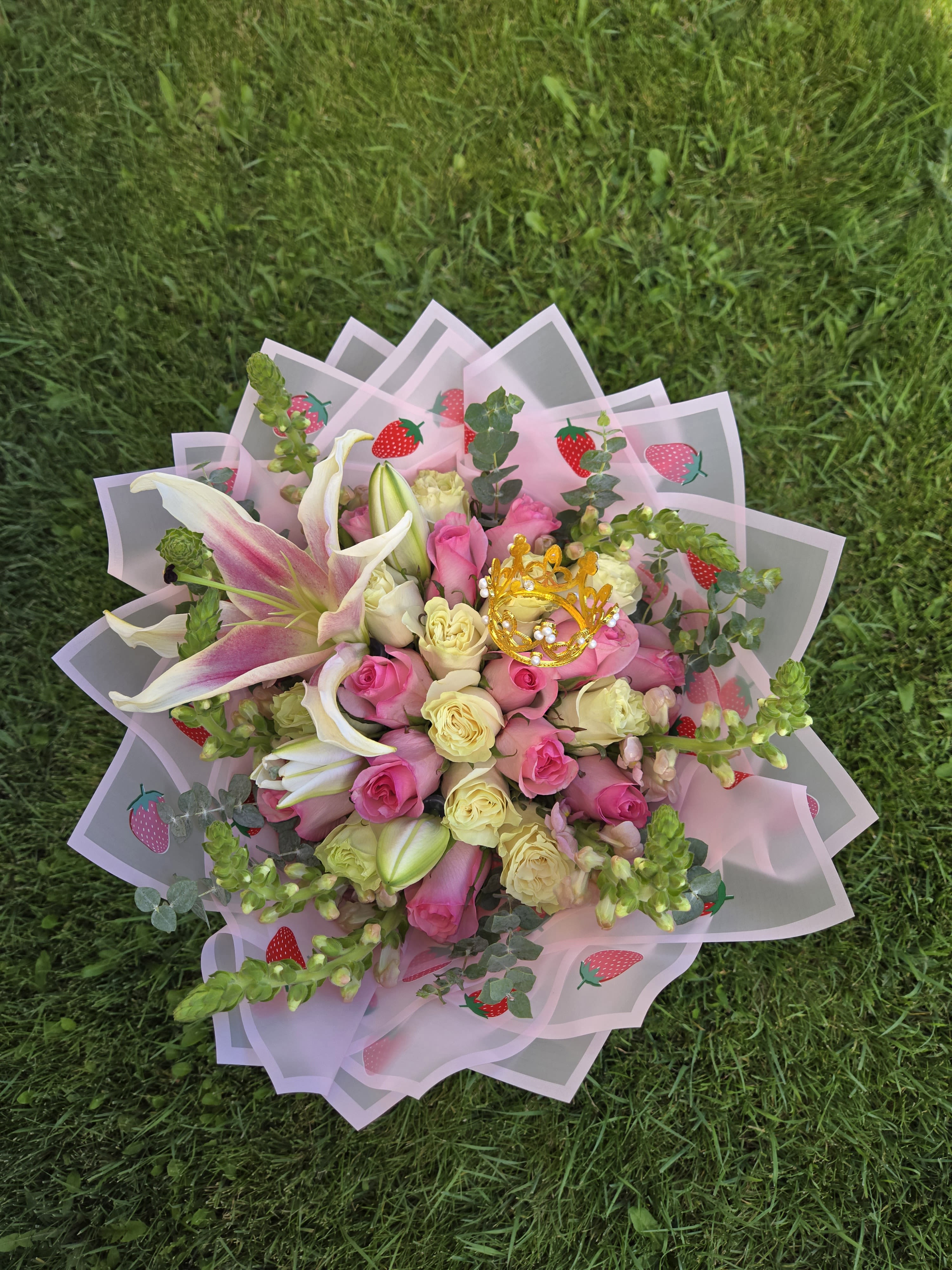 Pink and cream rose bouquet with lilies in strawberry-patterned wrap