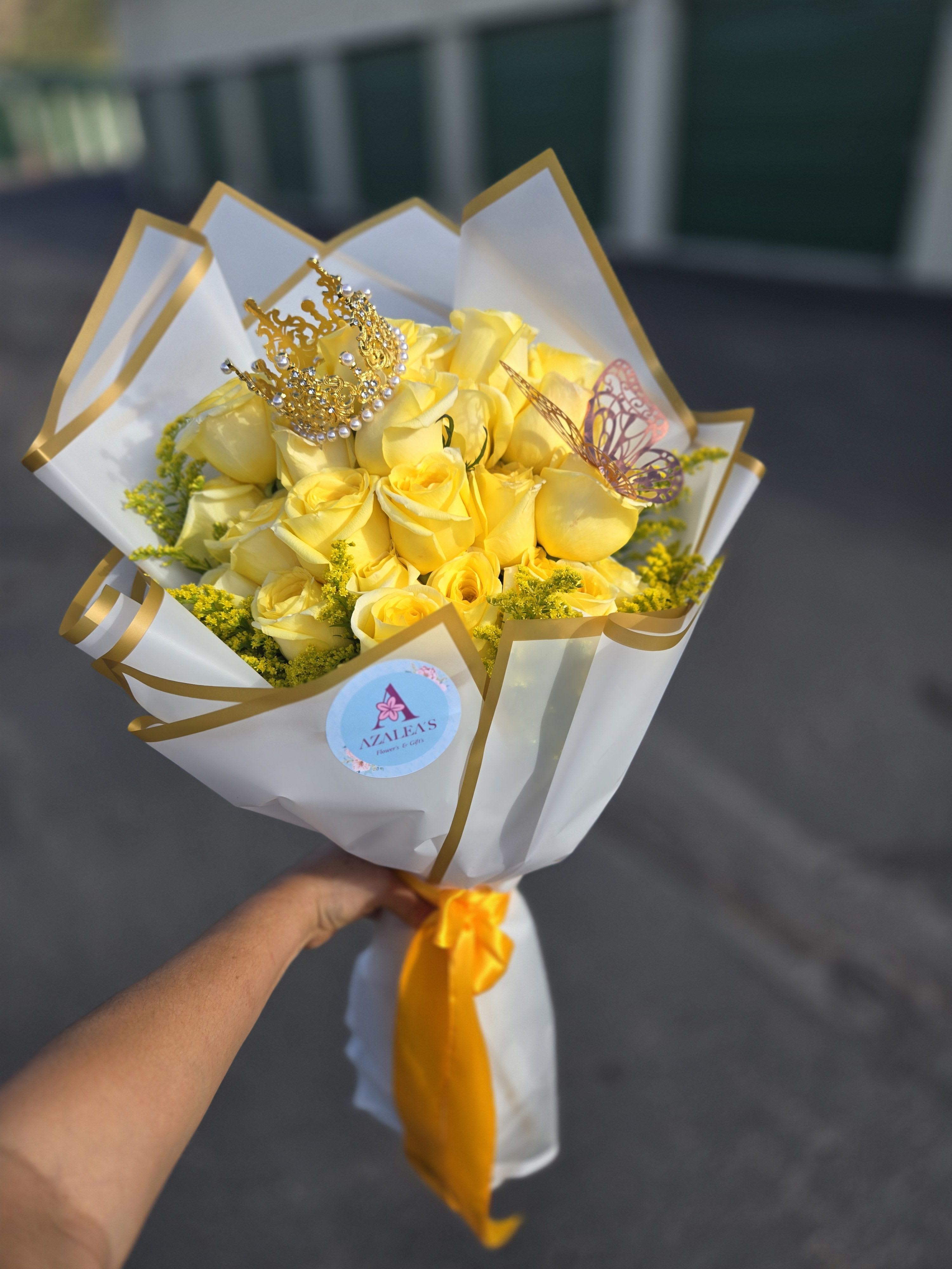 Yellow rose bouquet wrapped in white and gold paper with a decorative crown