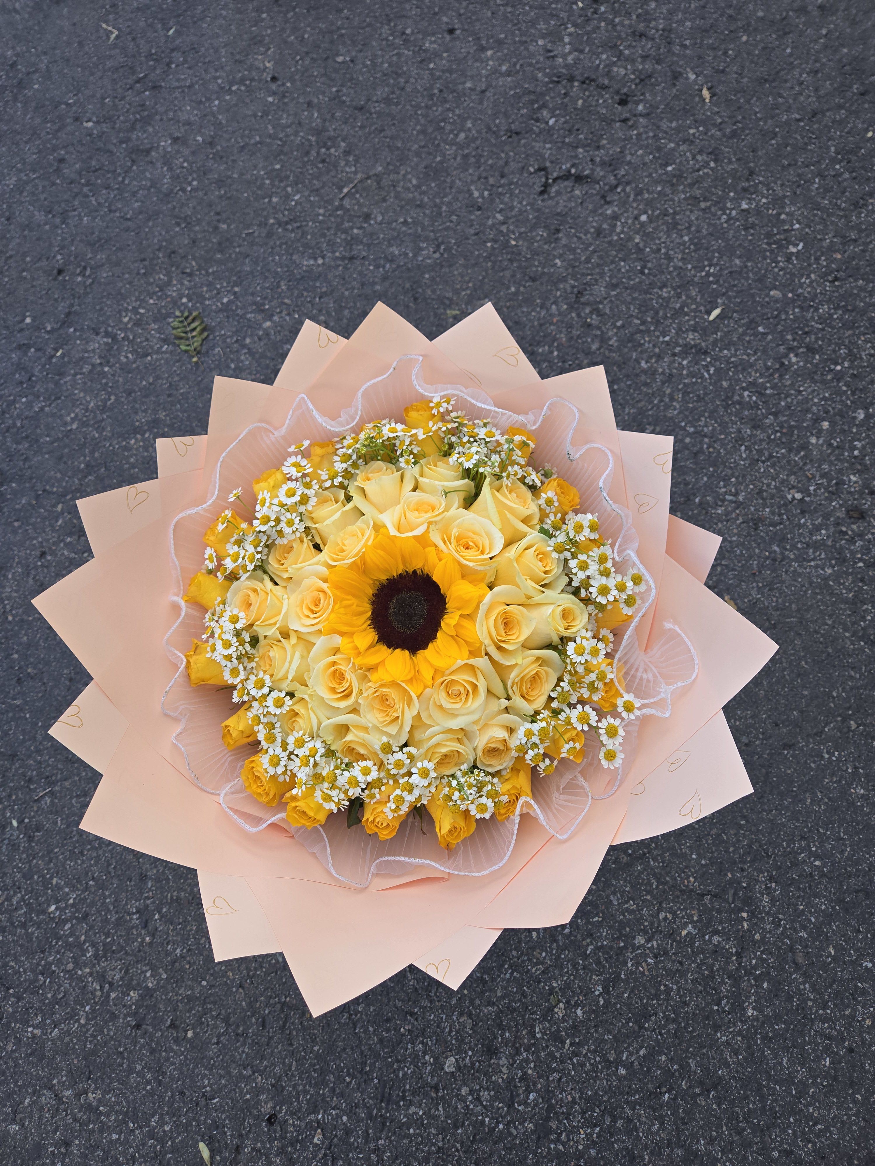 Yellow roses and a sunflower bouquet wrapped in pale pink paper