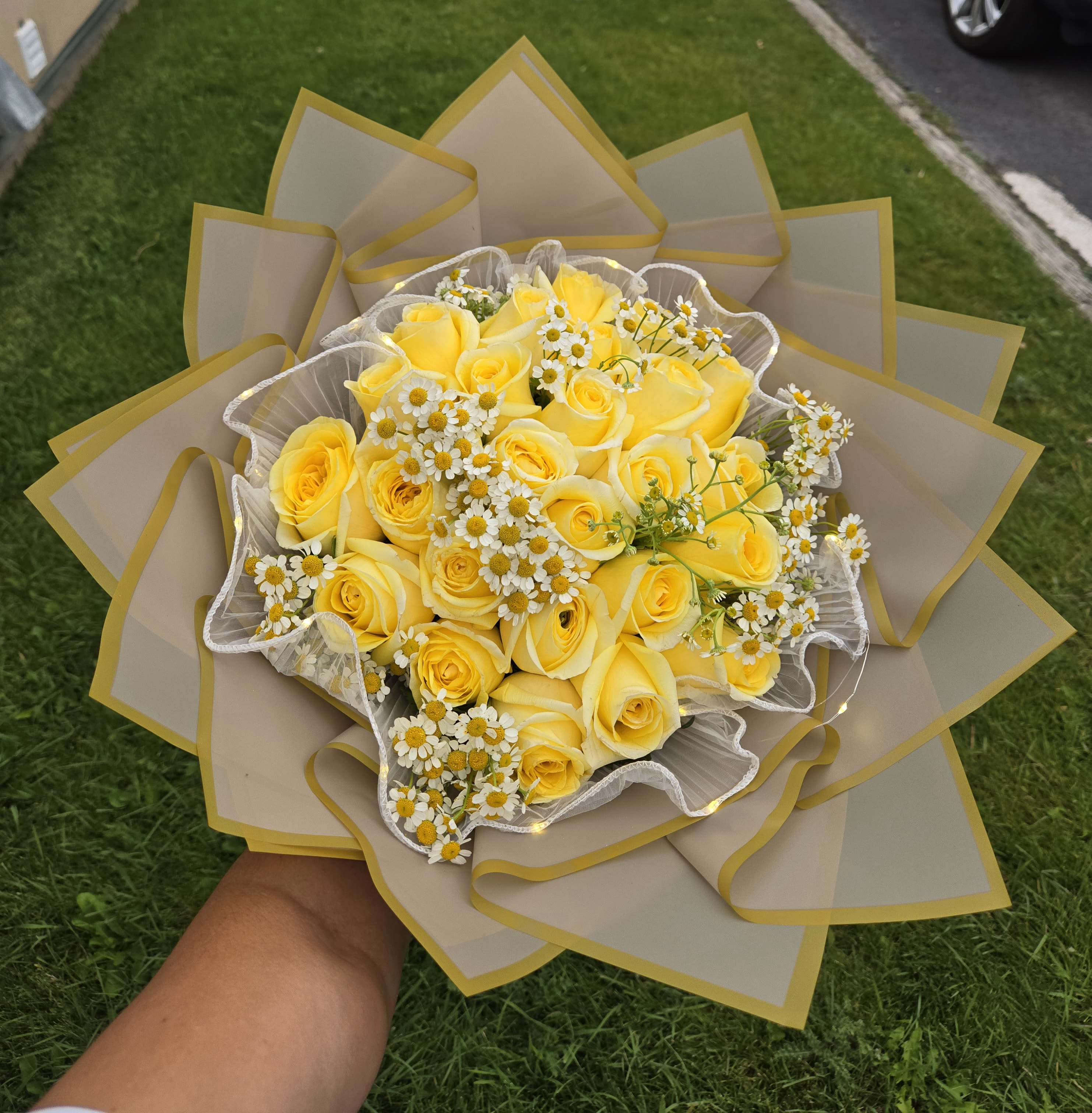 Yellow rose bouquet with small white daisies wrapped in beige paper