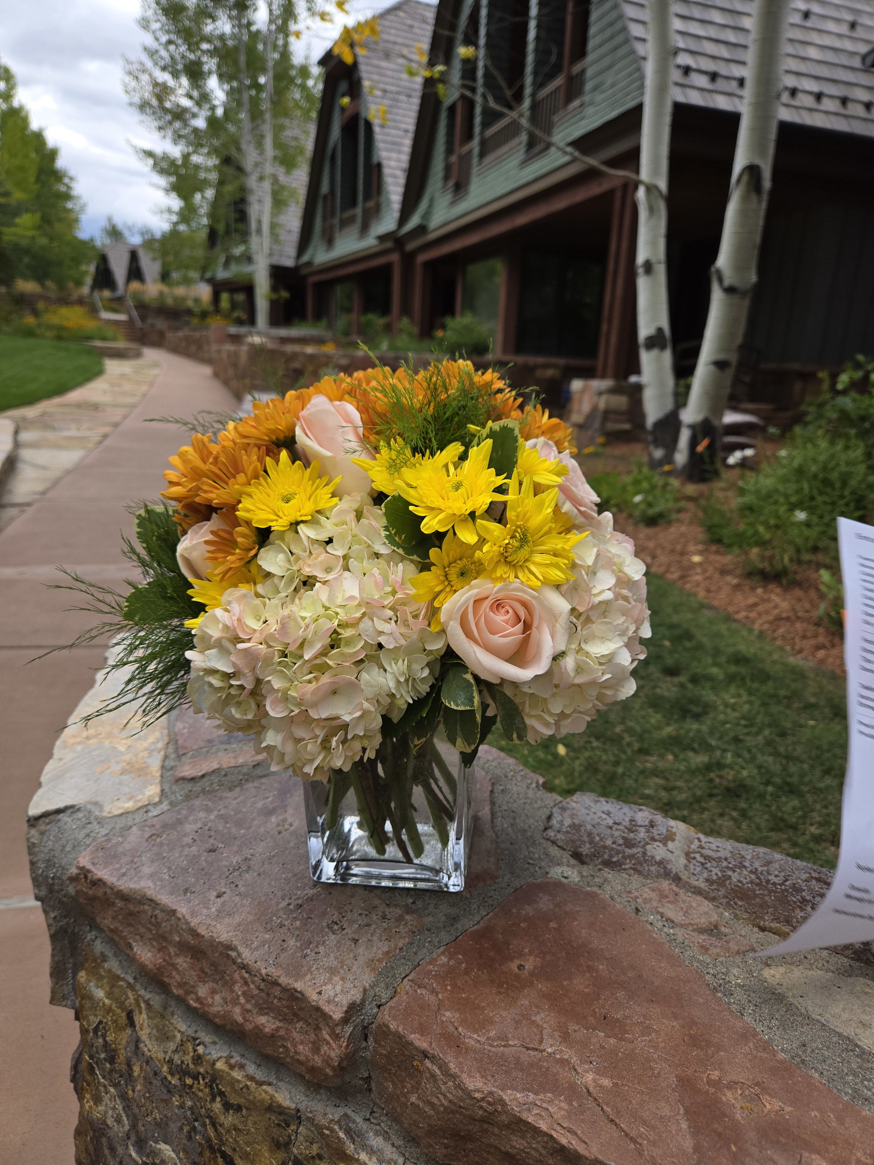 Bouquet of yellow and blush flowers in a clear glass vase