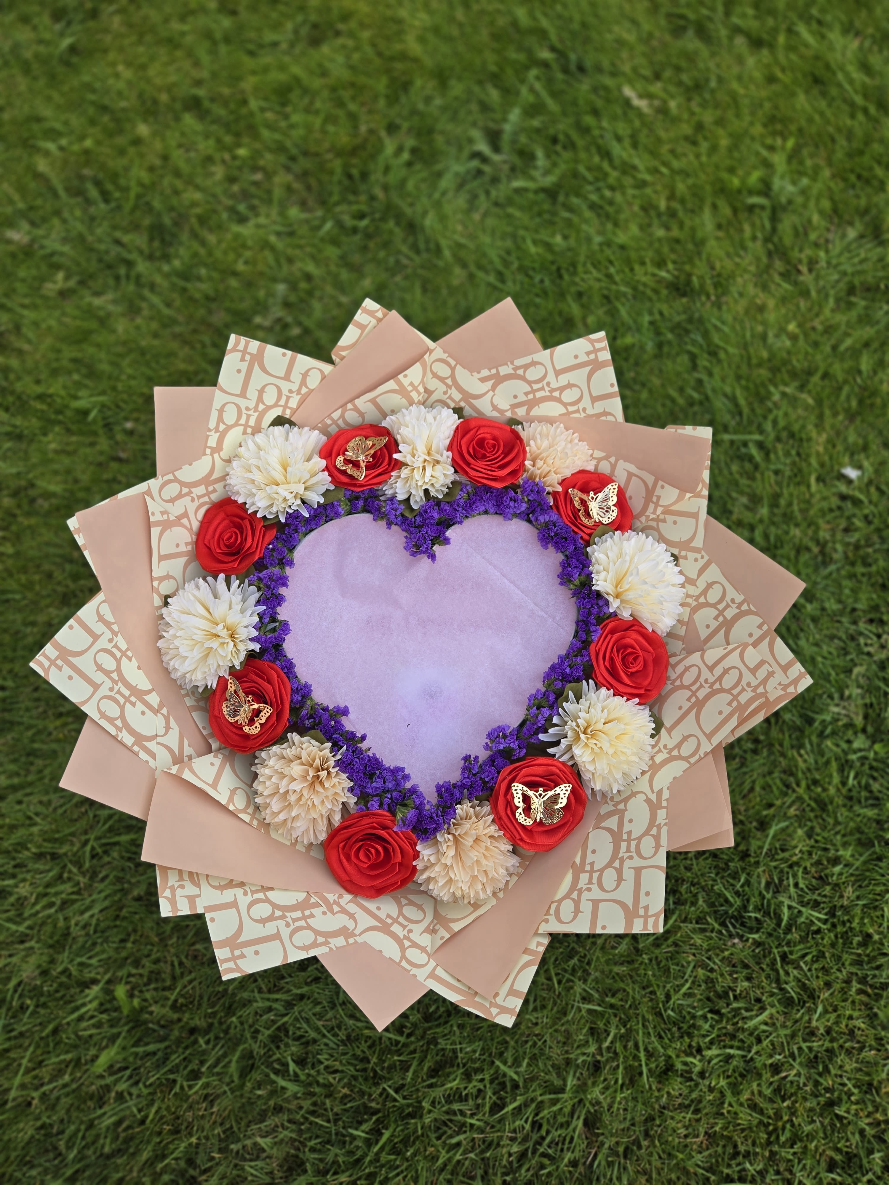 Heart-shaped bouquet with red roses and white blooms on pink wrapping