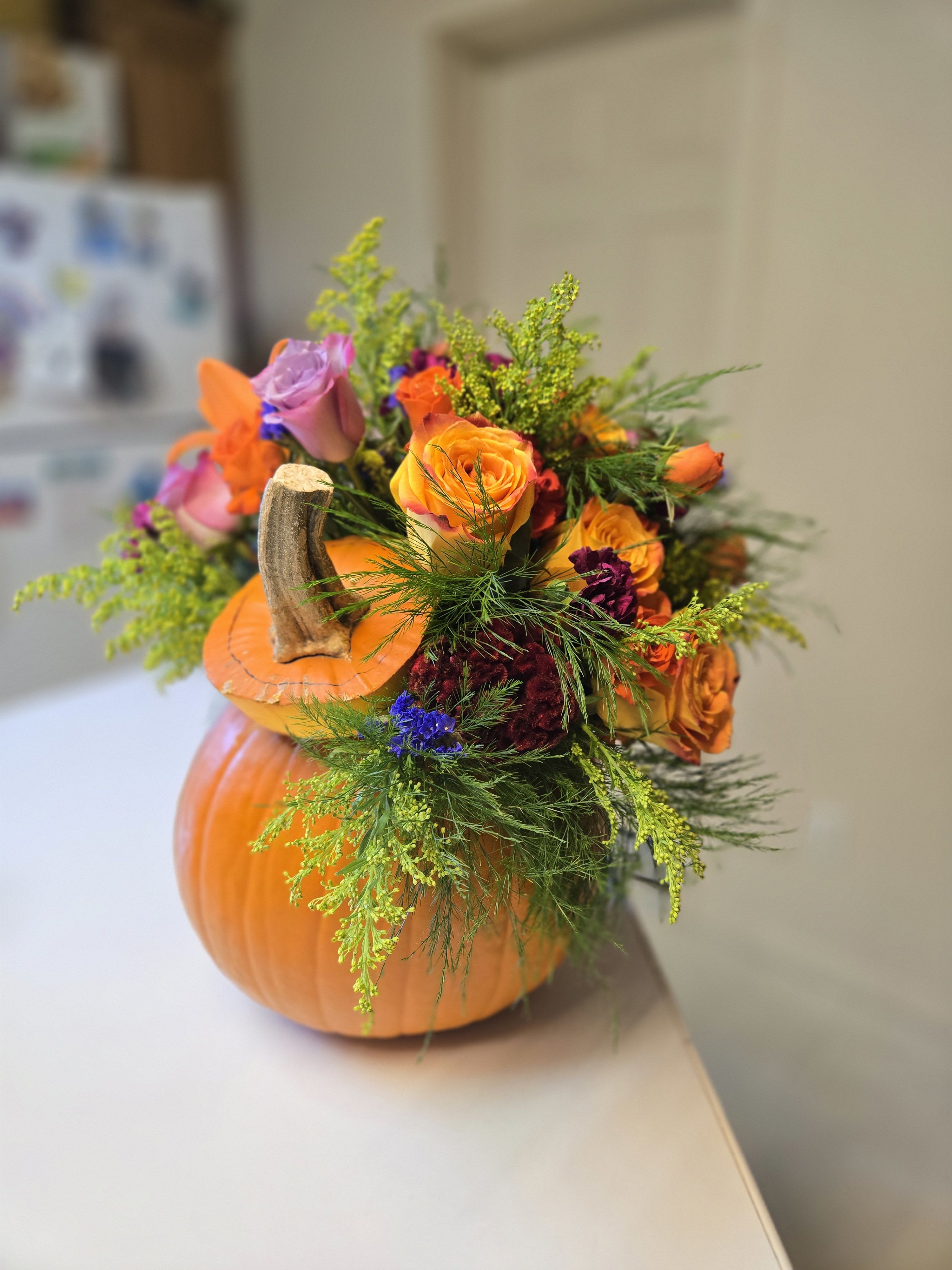 Pumpkin-shaped floral arrangement with orange and purple roses