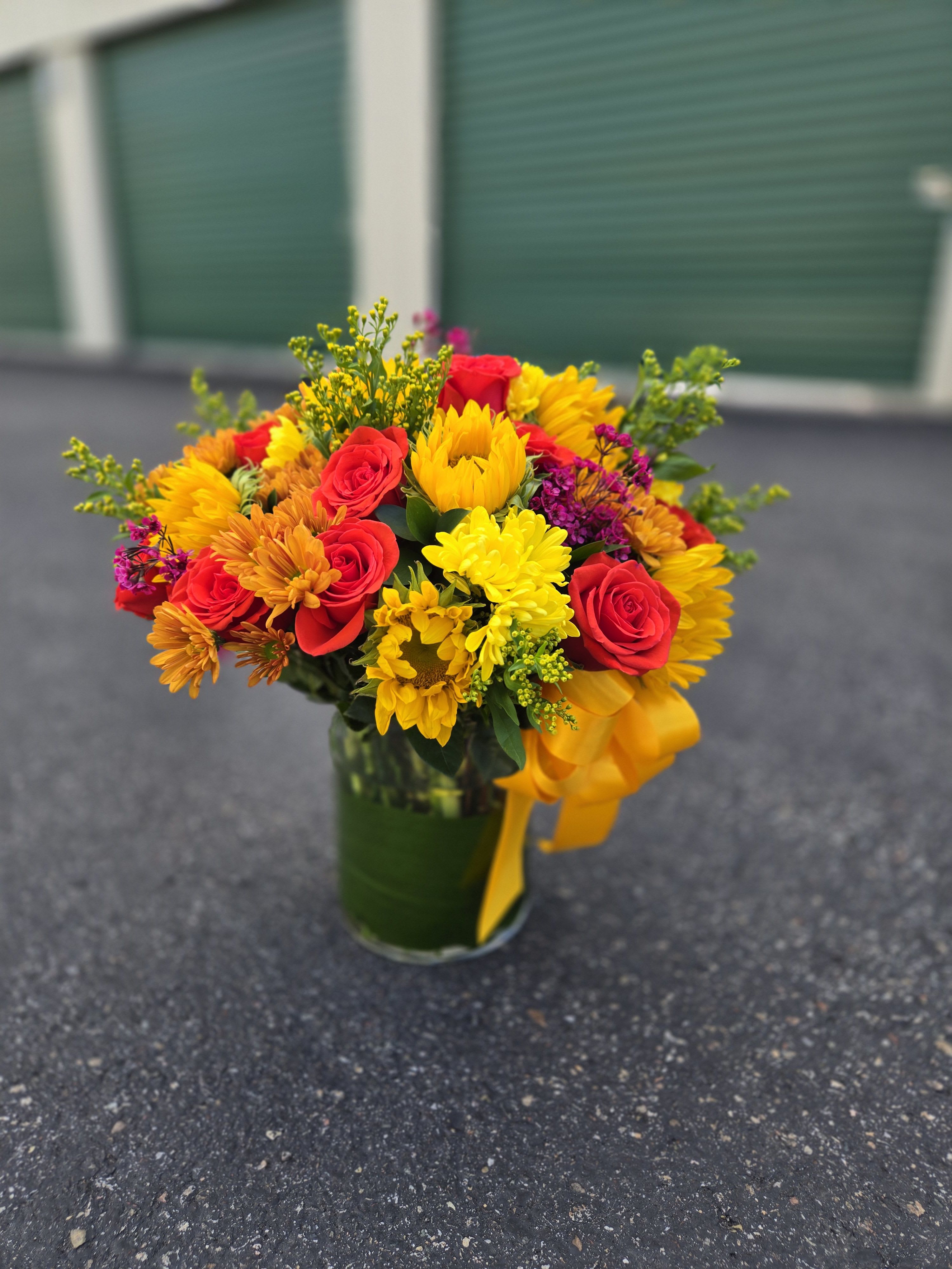 Bright mixed bouquet of red roses and yellow flowers in a glass vase