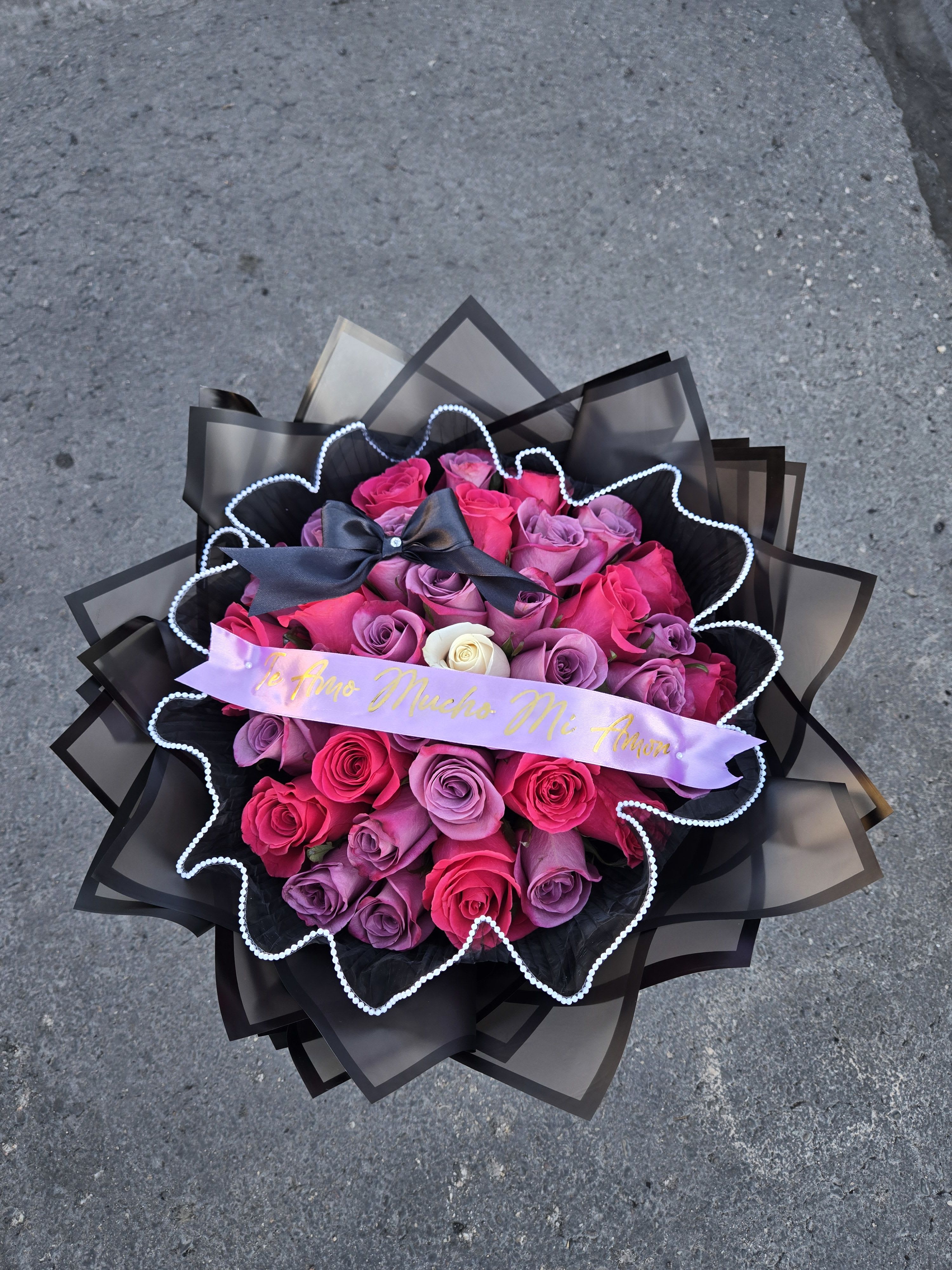 Bouquet of pink and purple roses with a black ribbon and decorative wrap